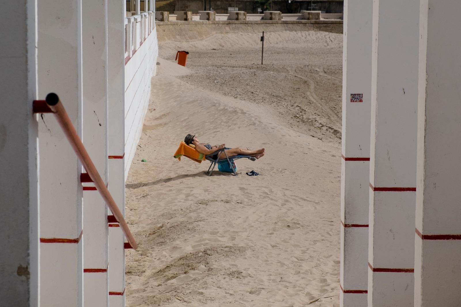 Una persona toma el sol en la playa de la Victoria de Cádiz.