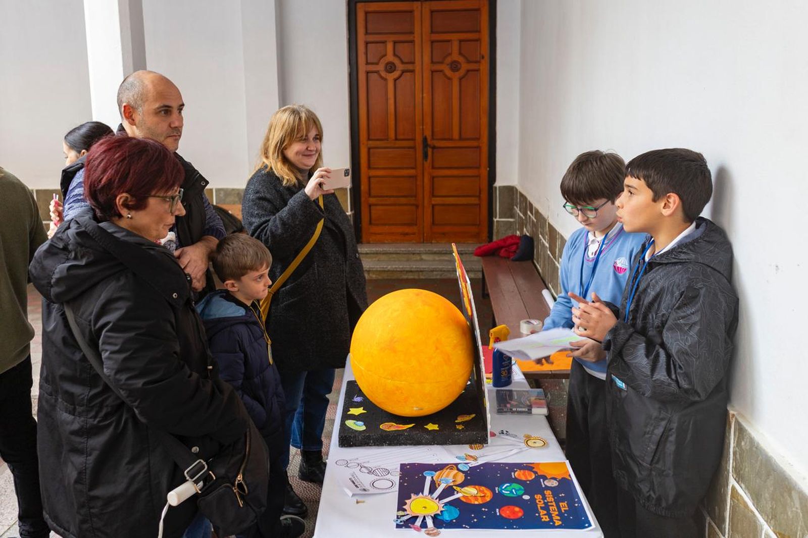 Visitantes escuchan las explicaciones de unos alumnos sober el sol.