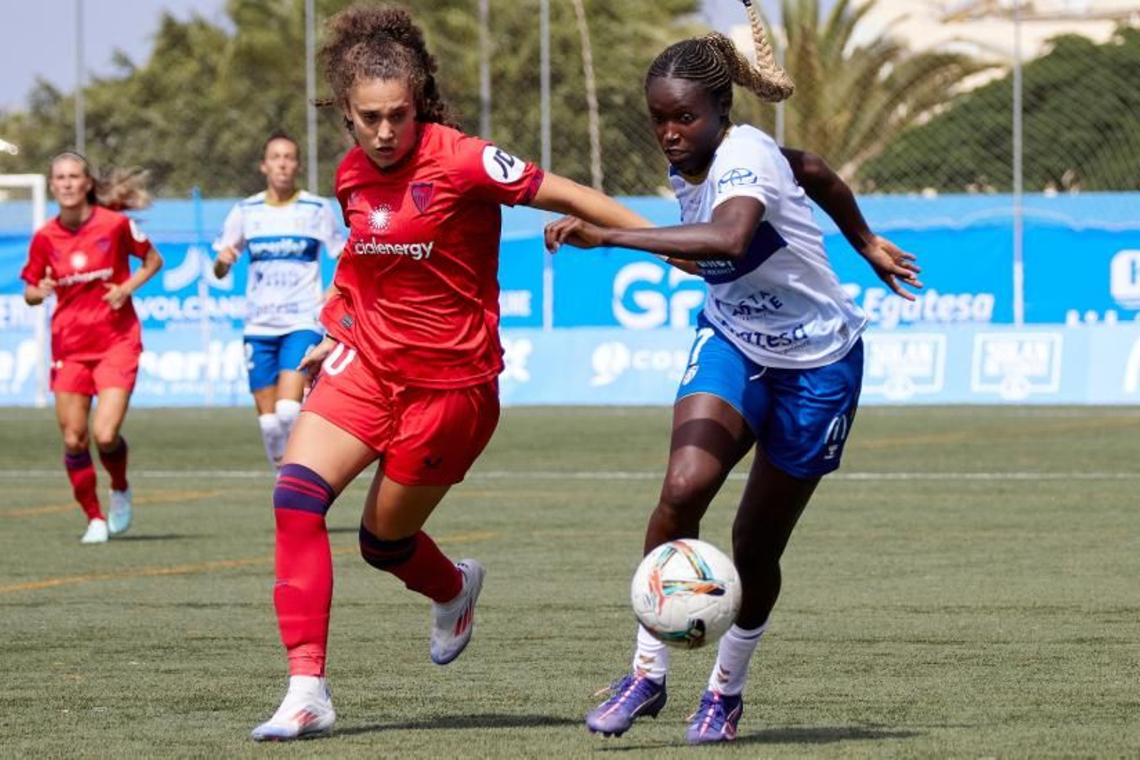 La sevillista Paula Partido y Babajide pugnan por el balón.
