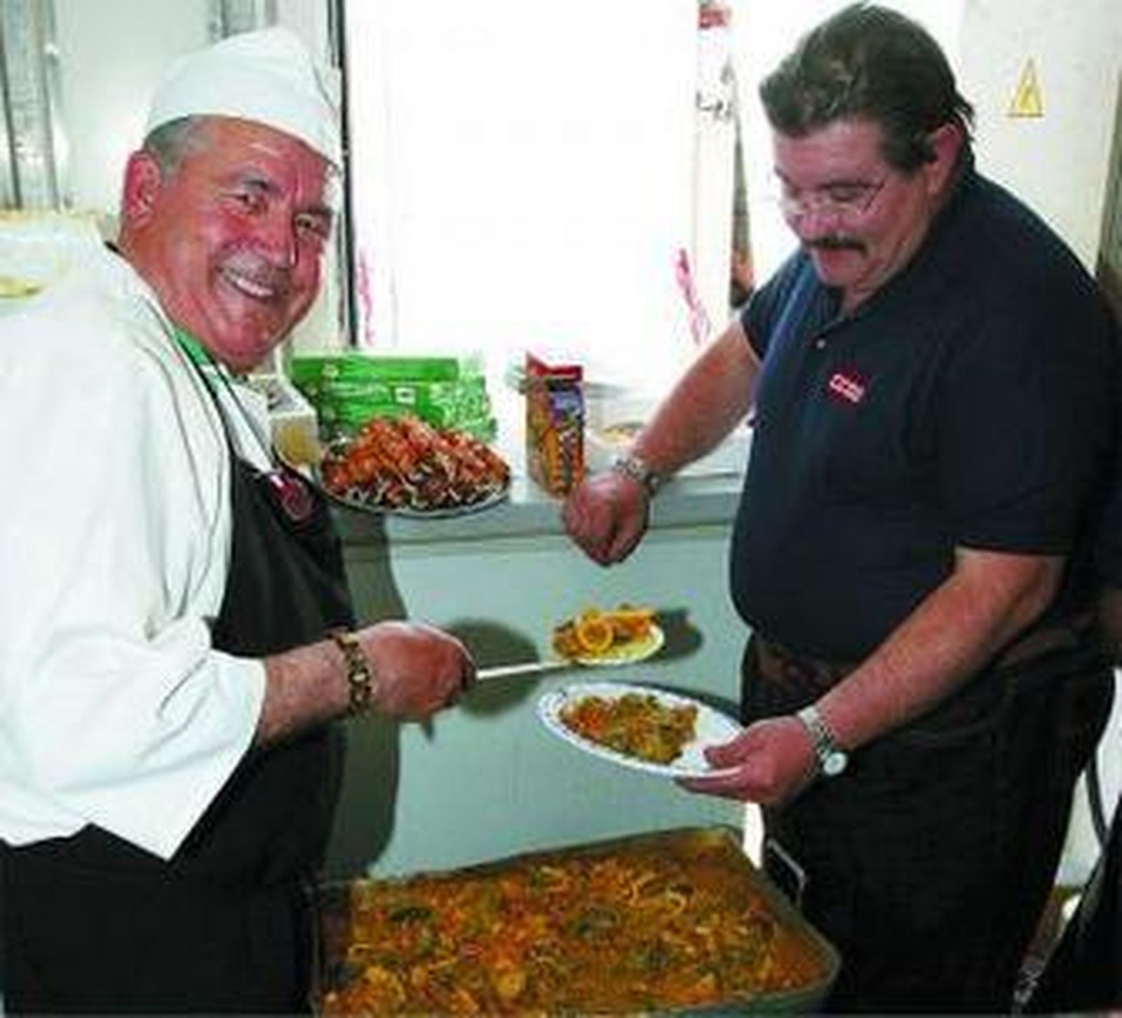 Trillo ayuda ayer al mediodía al cocinero a servir unos platos de rica paella.