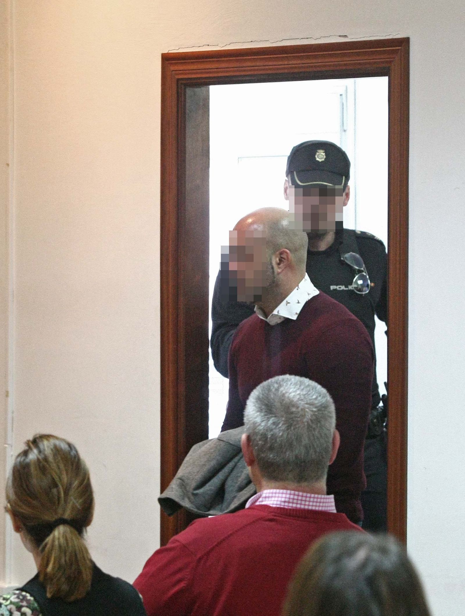 El acusado entra en la sala de vistas custodiado por un policía.