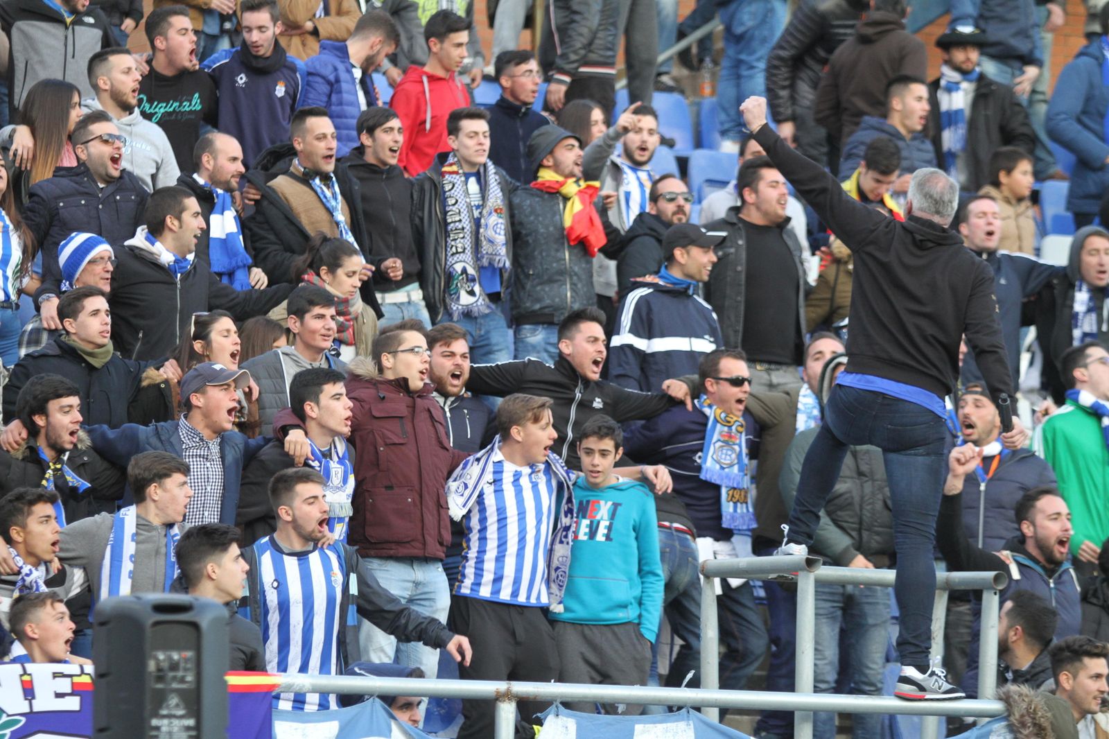 1. La grada de animación alentó a los recreativistas durante todo el encuentro. 2. Manolo Zambrano recibe la Medalla de Huelva de manos de Rubén Jiménez, directivo del Trust. 3. La afición respondió. 4. El palco, repleto. 5. Las aficionadas se protegen del frío. 6. Pavón vio un nuevo encuentro desde la grada. 7. Resignación entre los recreativistas. 8. La mascota albiazul regresó al campo. 9. Dos aficionadas aplauden a la salida del Decano al campo. 10. El colegiado fue muy protestado.
