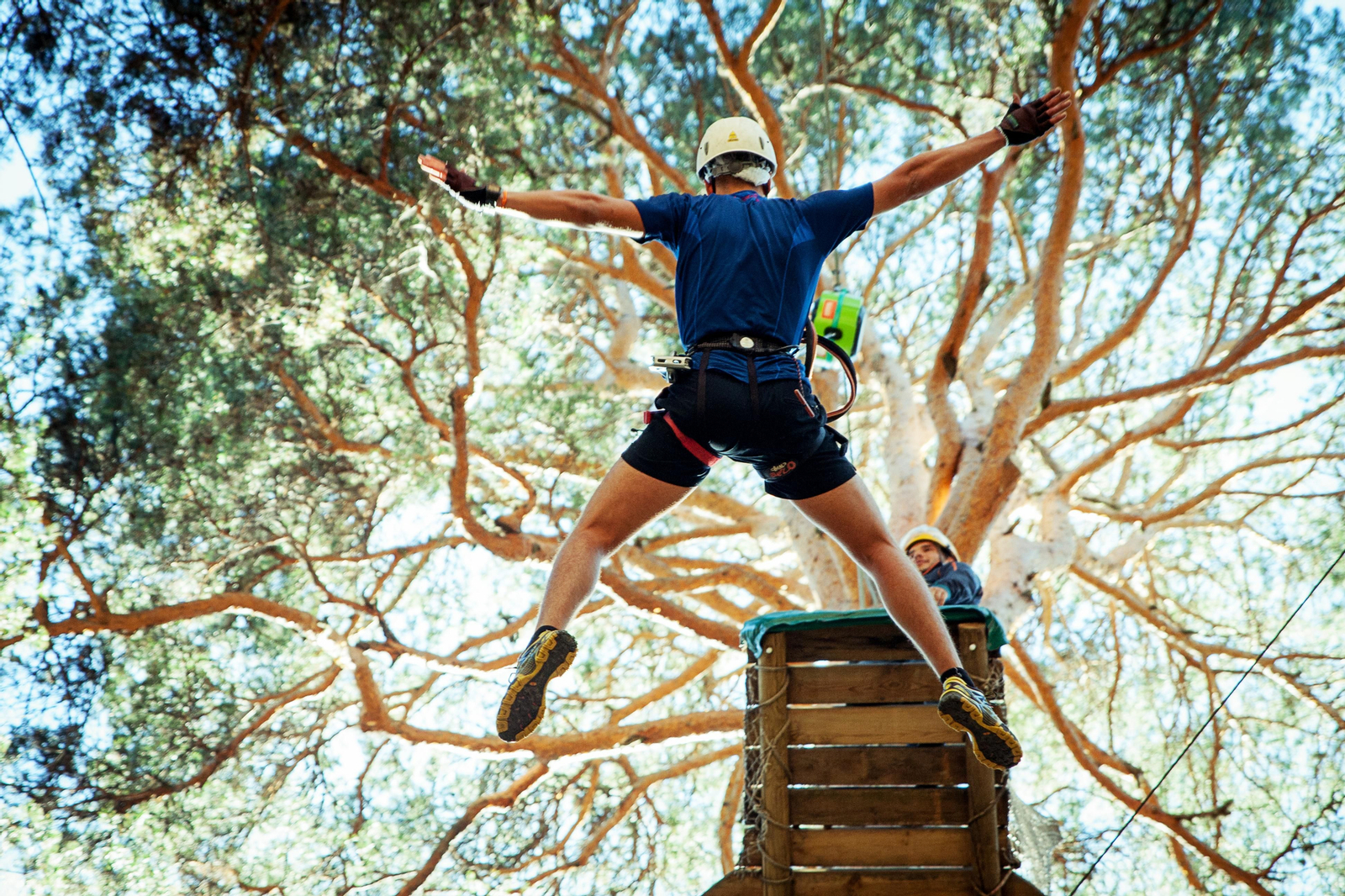 Una persona salta desde un árbol en una de las actividades del parque de aventuras.