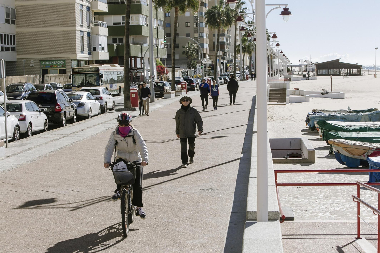Un hombre monta en bicicleta por la acera del Paseo Marítimo junto a los peatones.