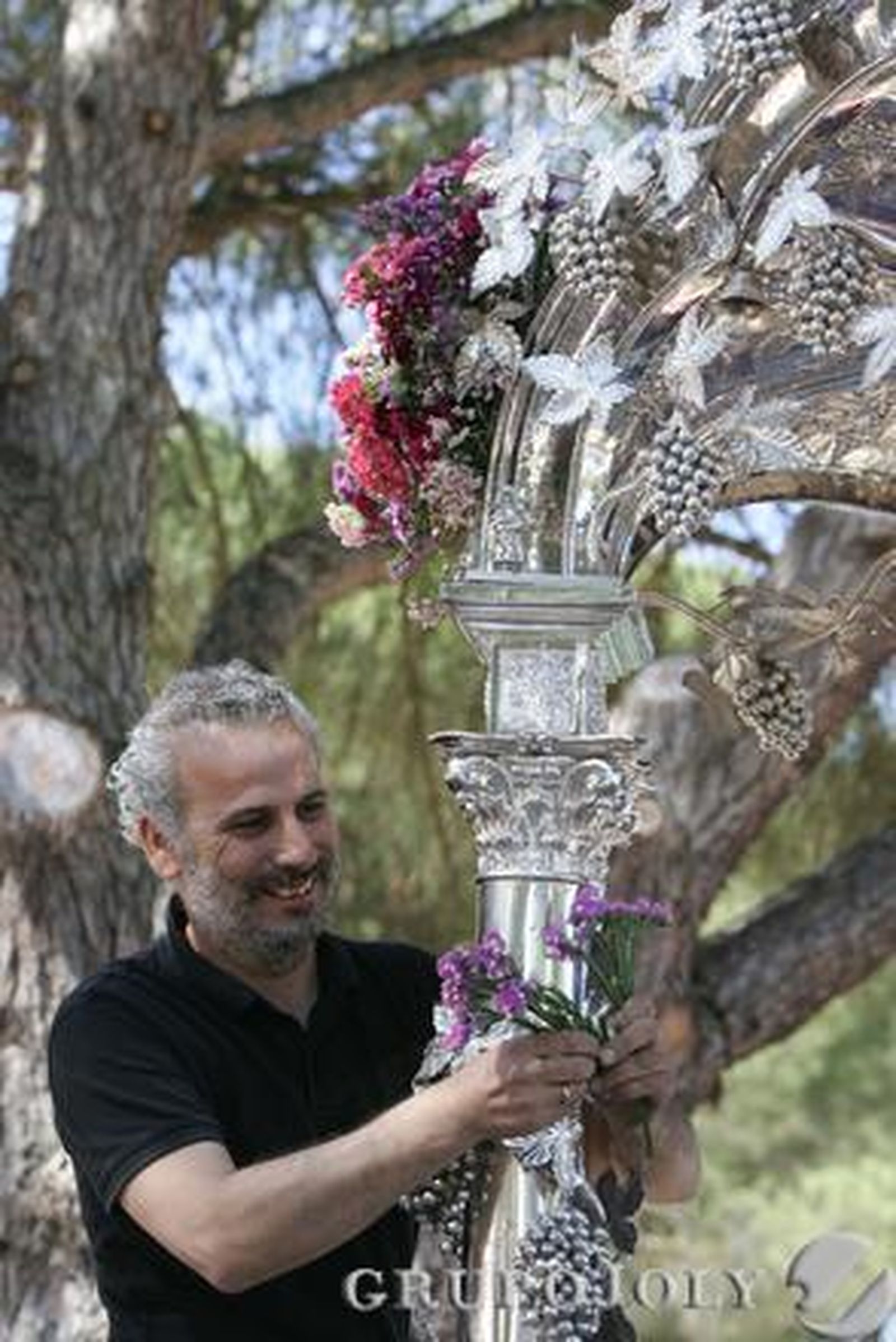 Un rociero coloca las flores, en tonos morado y rosa, en la carreta  Foto: Pascual