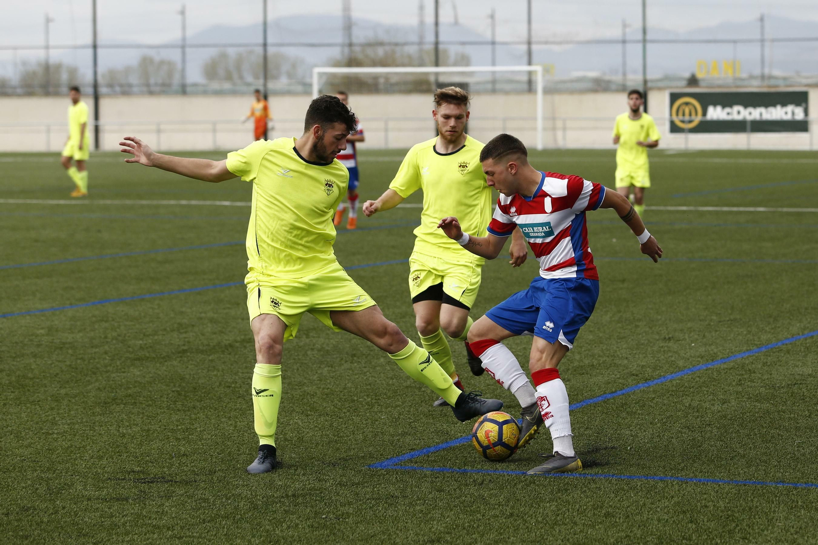 Dos jugadores del Séneca presionan a un jugador del Granada.