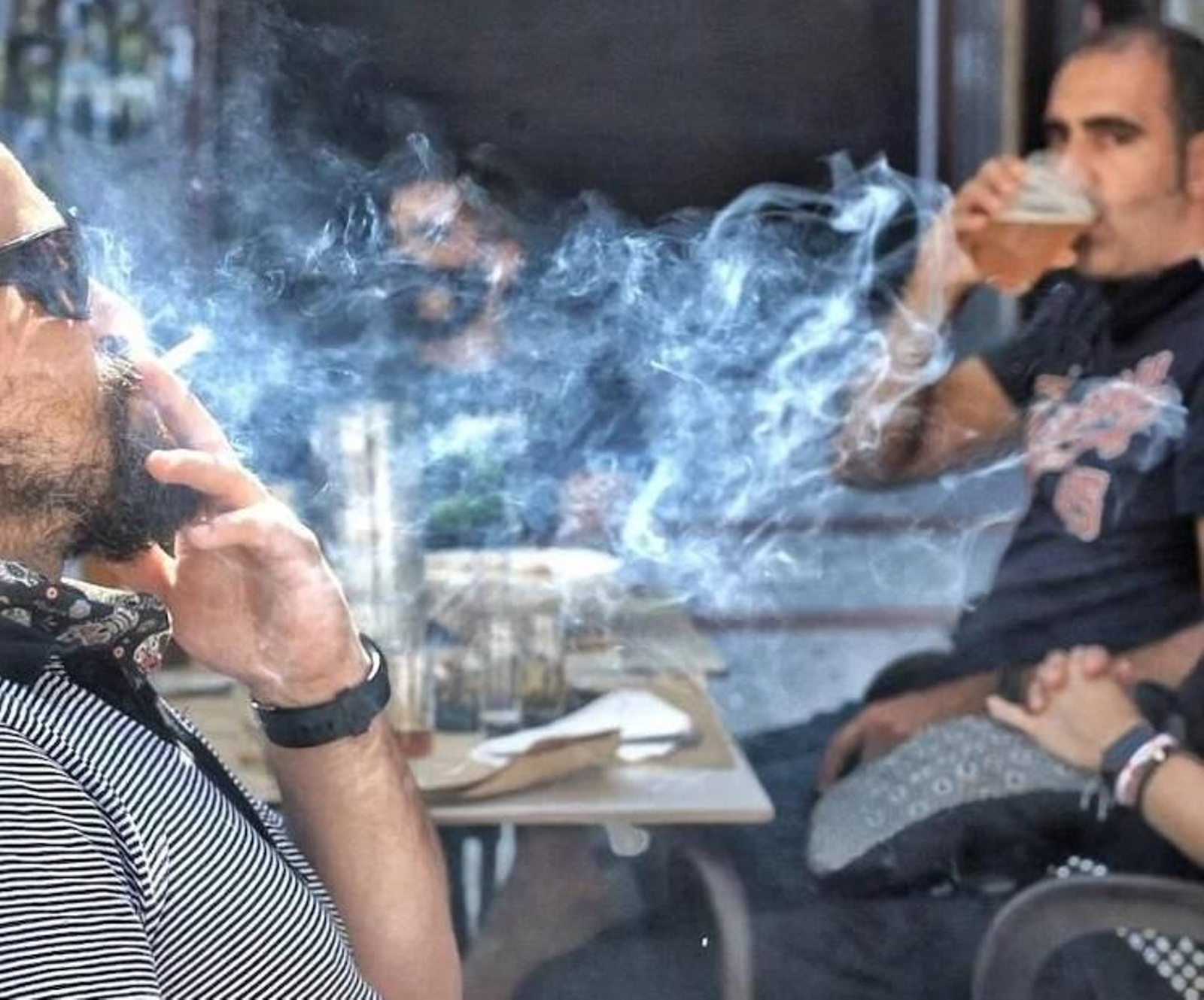 Señor fumando en la terraza de un bar.