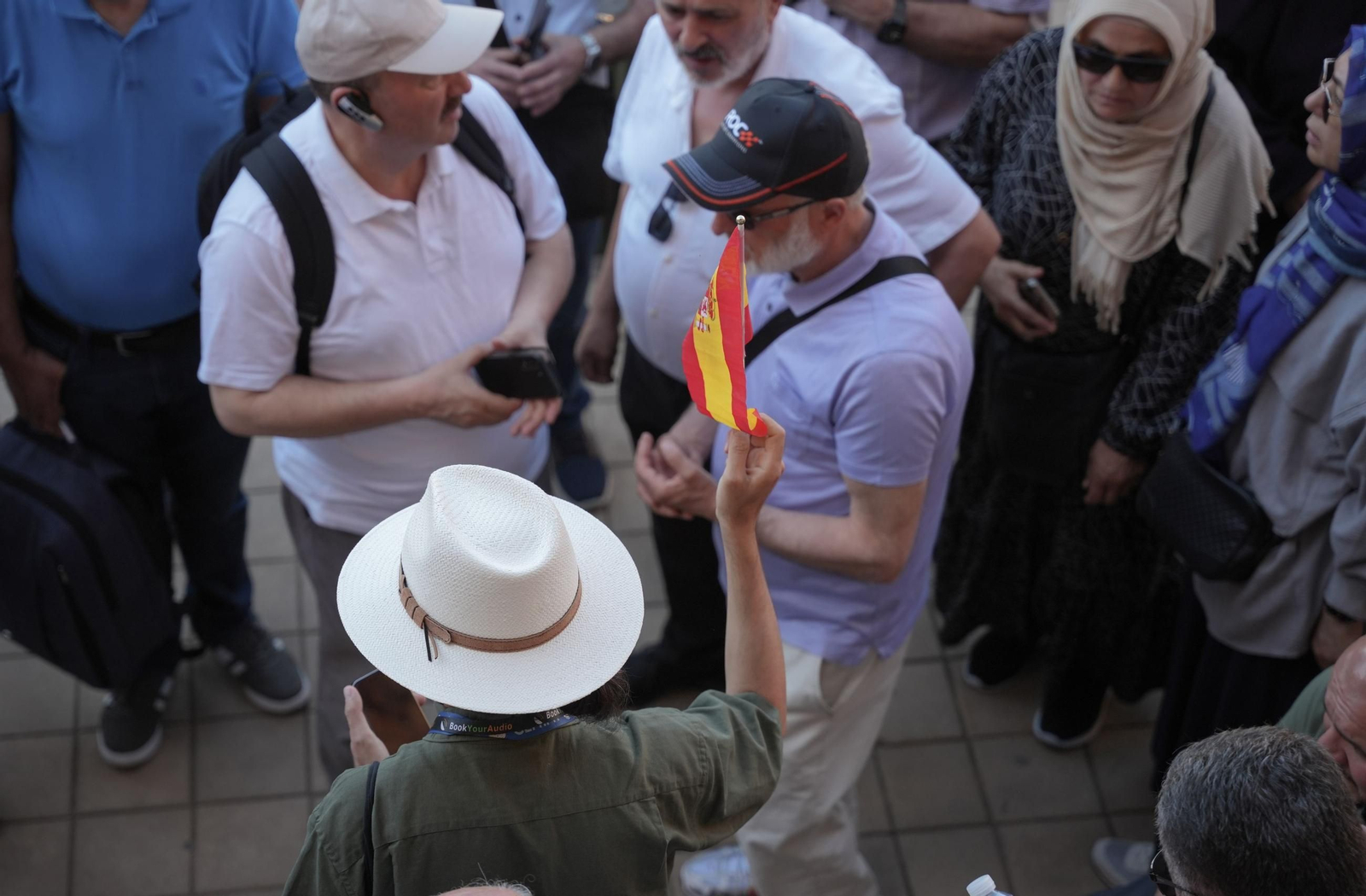 Un guía  turístico  sujeta una bandera de España en la Plaza de España en Sevilla