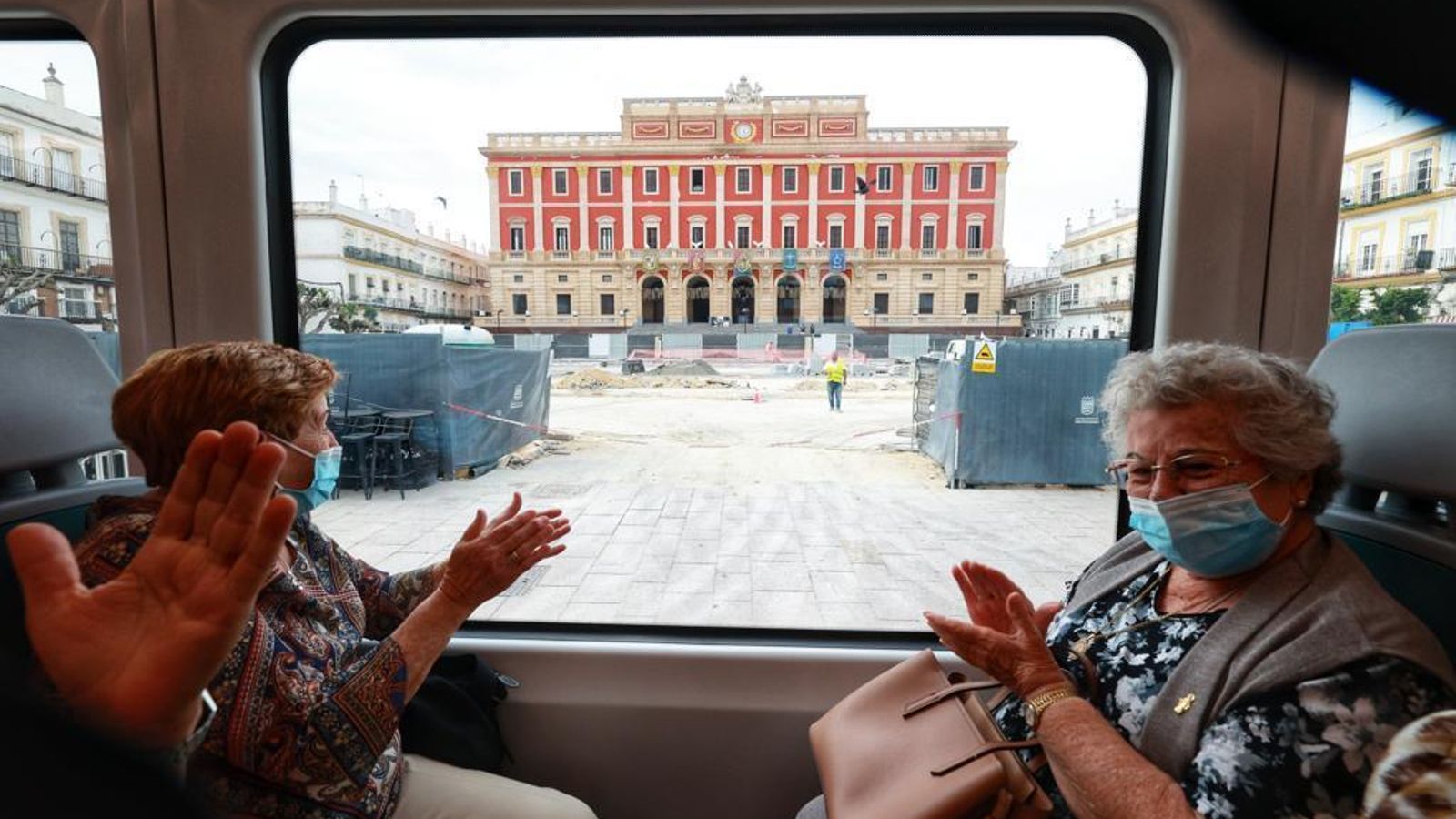 Viajeros procedentes de Chiclana pasan por delante del Ayuntamiento isleño.