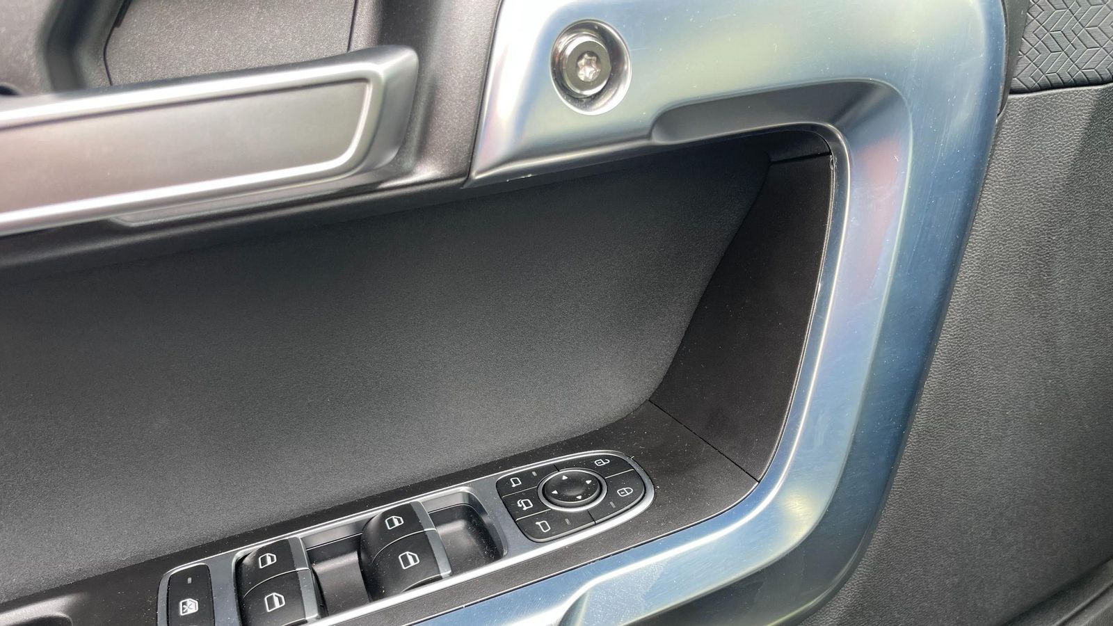 Un hueco por delante de los mandos de las puertas resolvería el problema de la ausencia de tirador en el panel del conductor.
