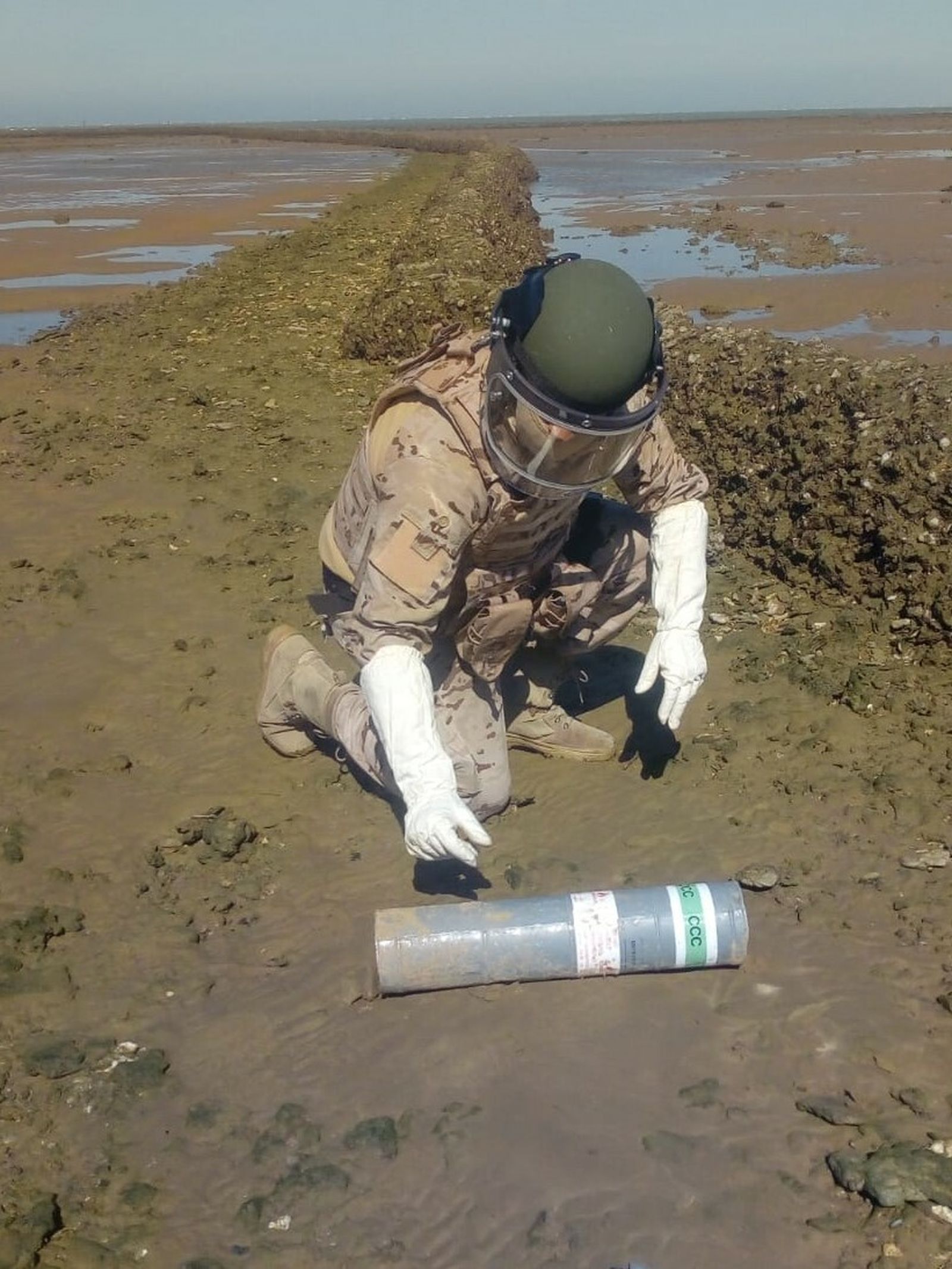 Un efectivo de la Armada neutraliza una bengala en la playa de la Jara, en Sanlúcar.