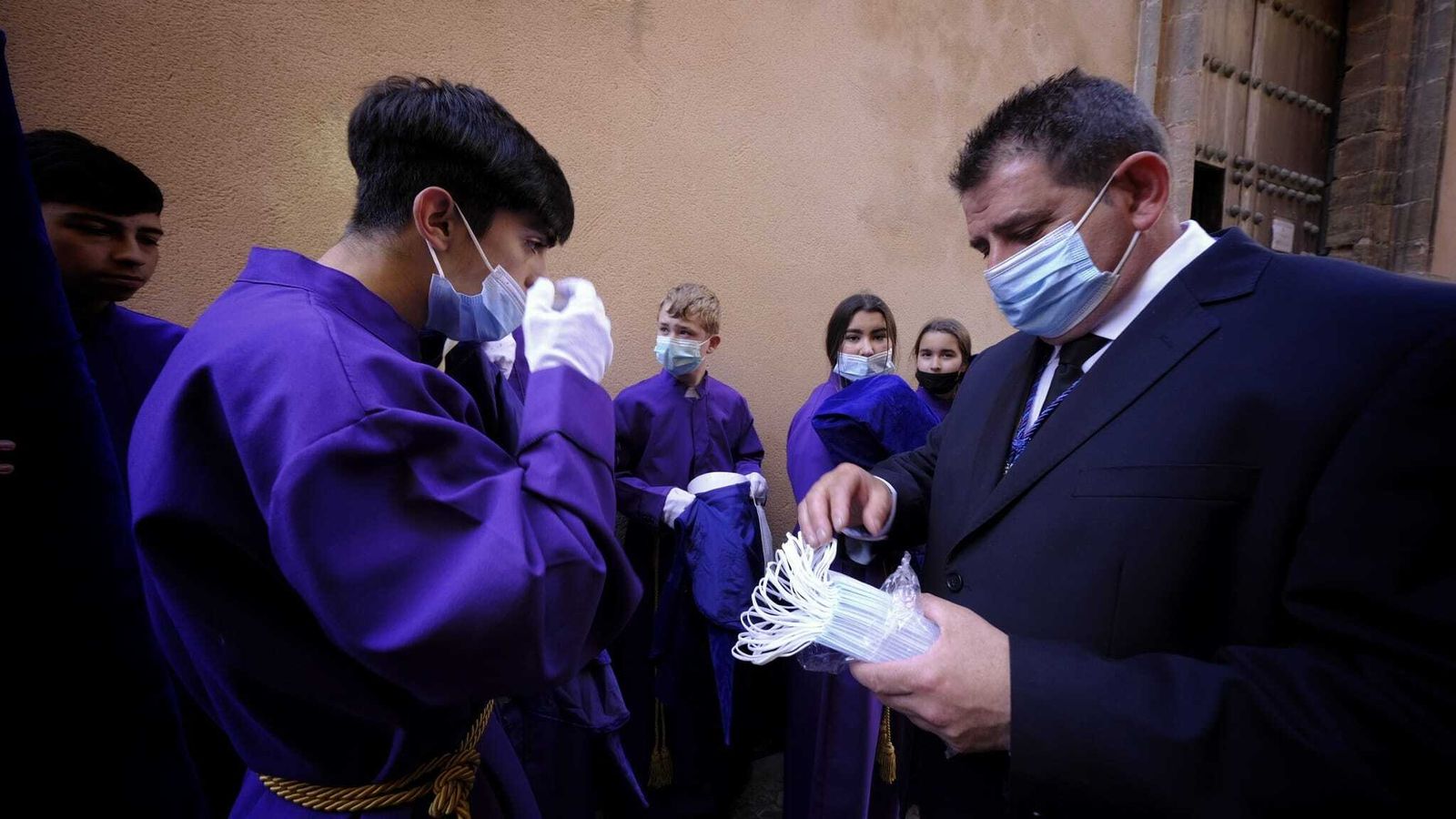 Un responsable de la cofradía de Afligidos reparte mascarillas entre los hermanos.
