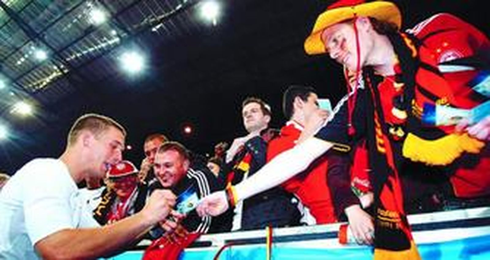 Lukas Podolski firma autógrafos a aficionados alemanes al término del partido que decidió con dos goles ante Polonia.