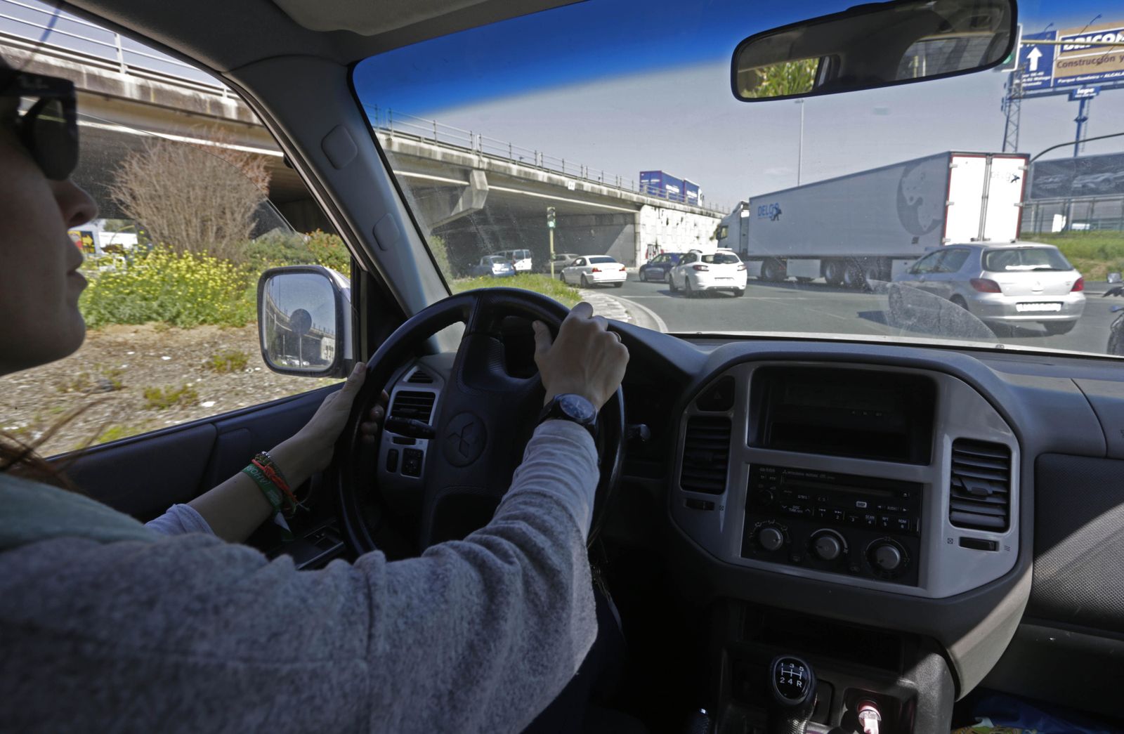 Una joven conduce un vehículo en una concurrida intersección.