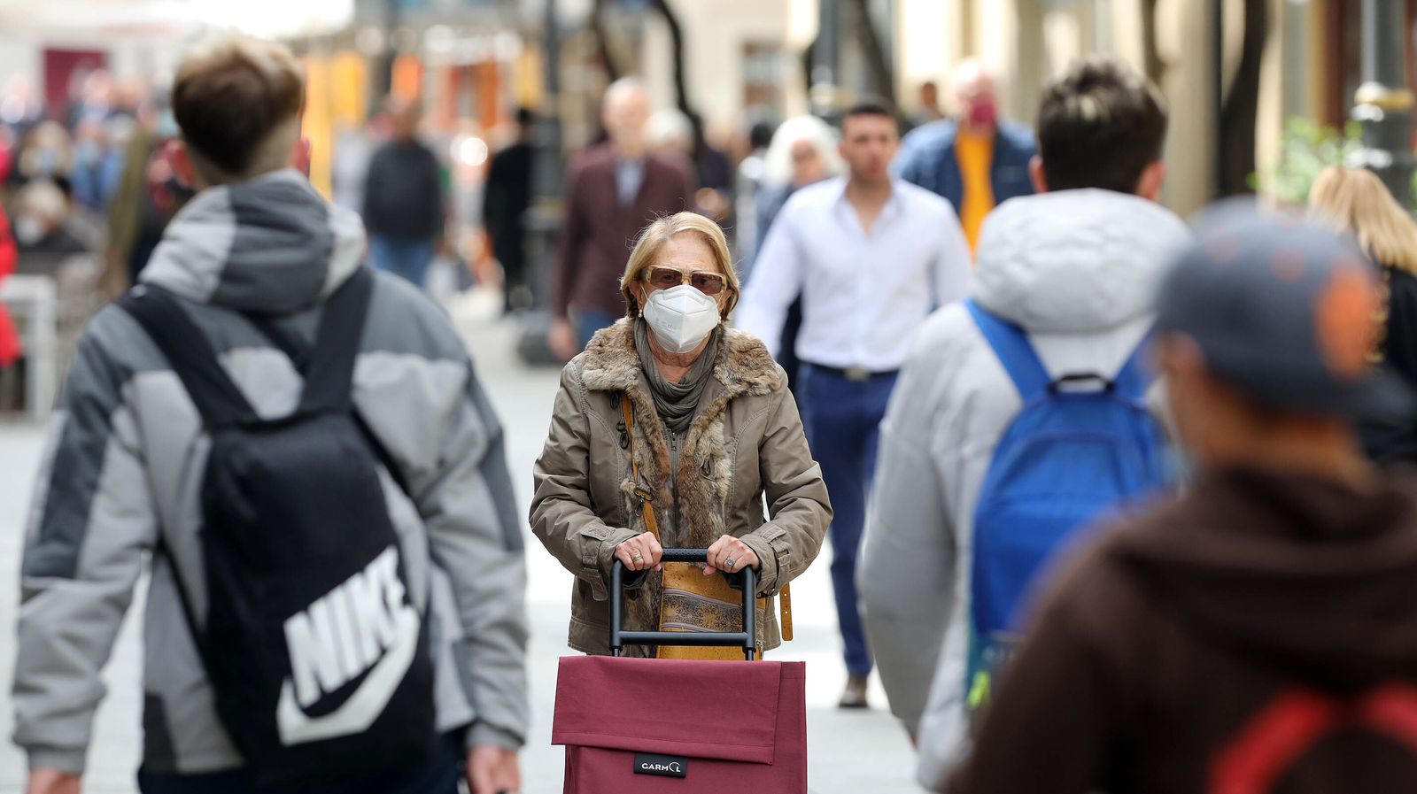 Una mujer con mascarilla por el centro, donde cada vez es más frecuente el abandono de su uso.
