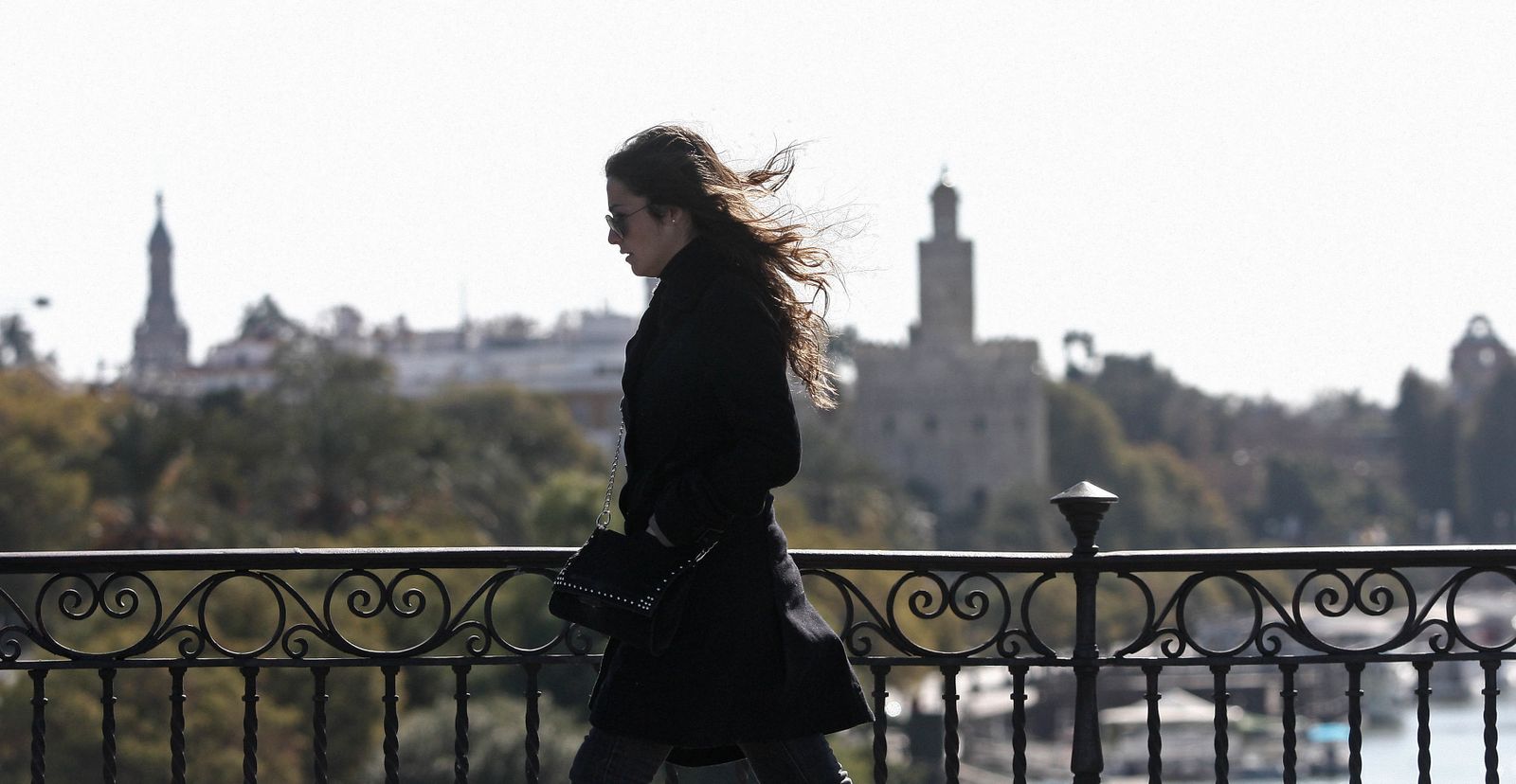 Una joven por el puente de Triana, con la Torre del Oro al fondo.