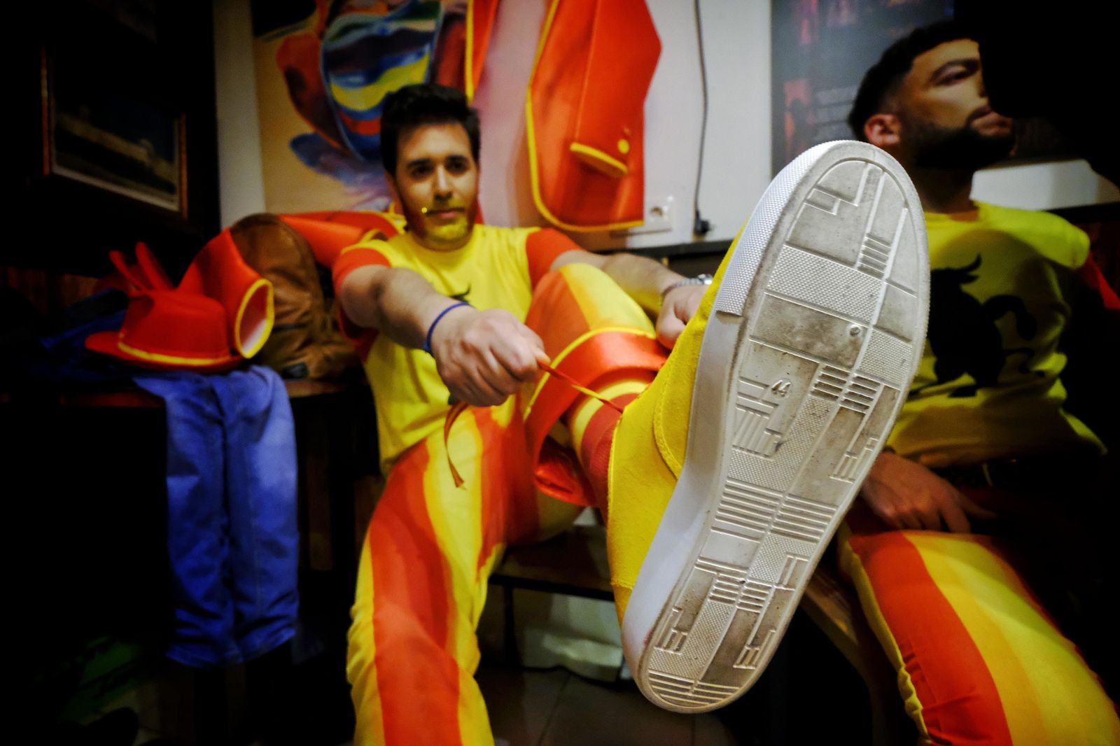 Uno de los componentes de 'Los dependentistas' se ata el cordón de los tenis también de color amarillo.