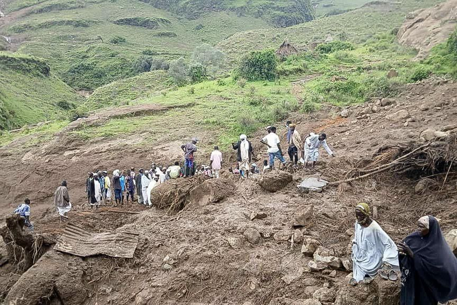 Varias personas caminan por el lugar del deslizamiento de tierra en Tarsin (Sudán).