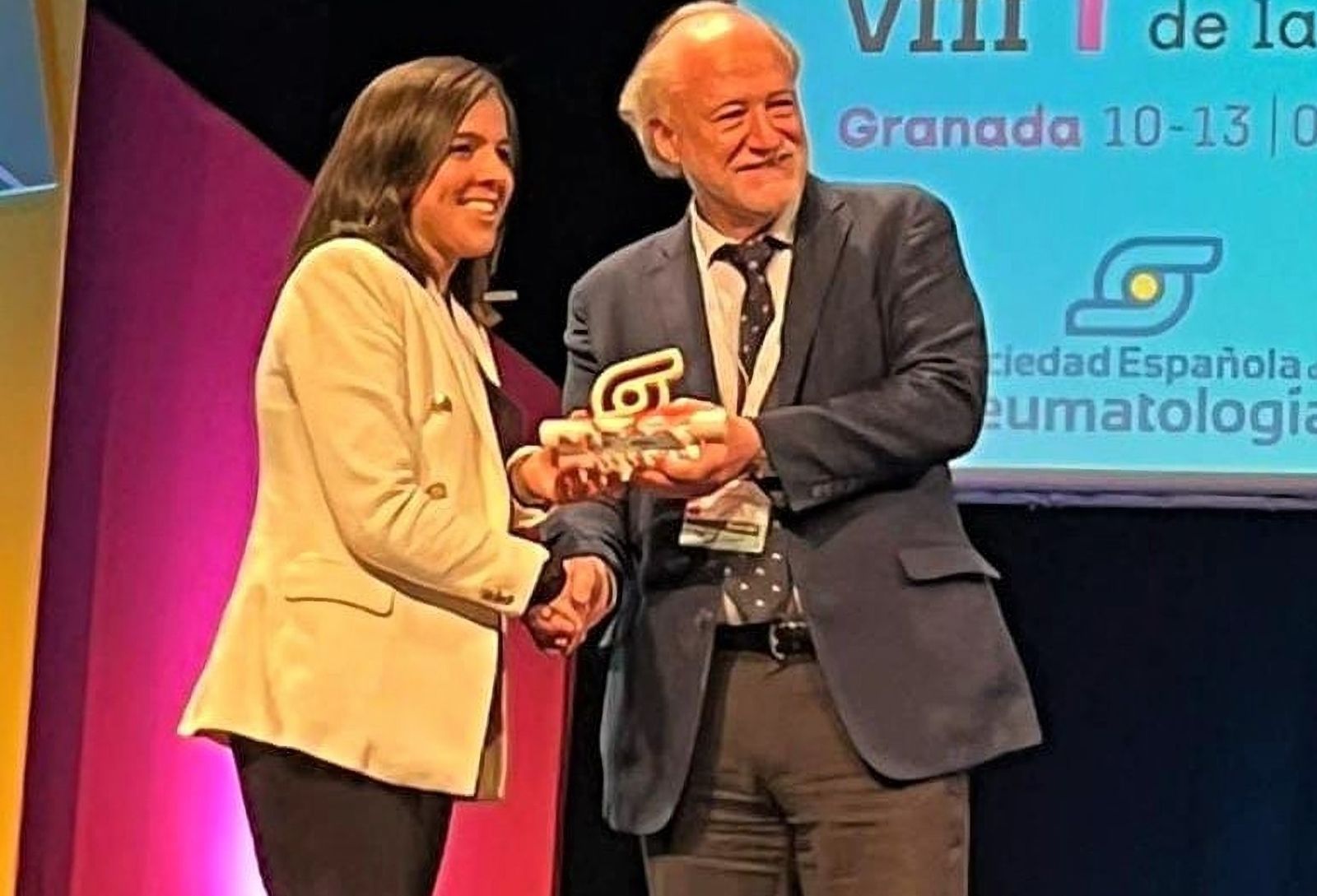Laura Bautista recoge el premio de manos del presidente de la Sociedad Española de Reumatología, José María Álvaro Gracia.