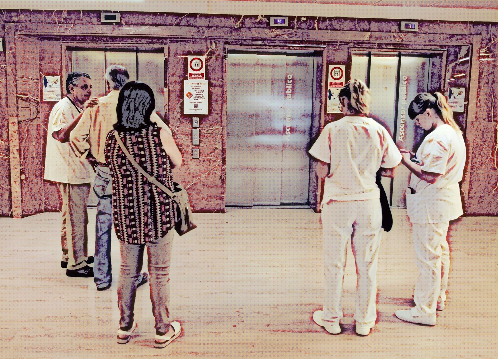 Usuarios y personal sanitario esperan un ascensor en un centro hospitalario.