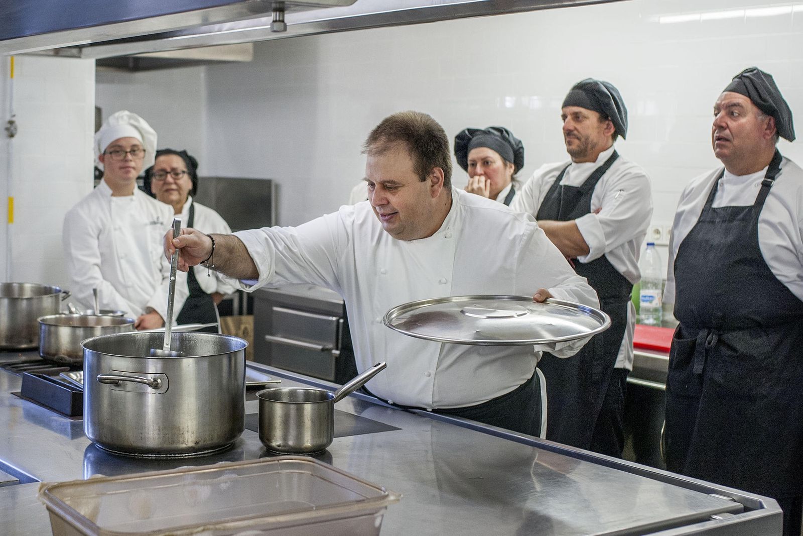 Sami García, uno de los discípulos de Santi Santamaría, jefe de cocina de Universo Santi, junto a algunos de los discapacitados.