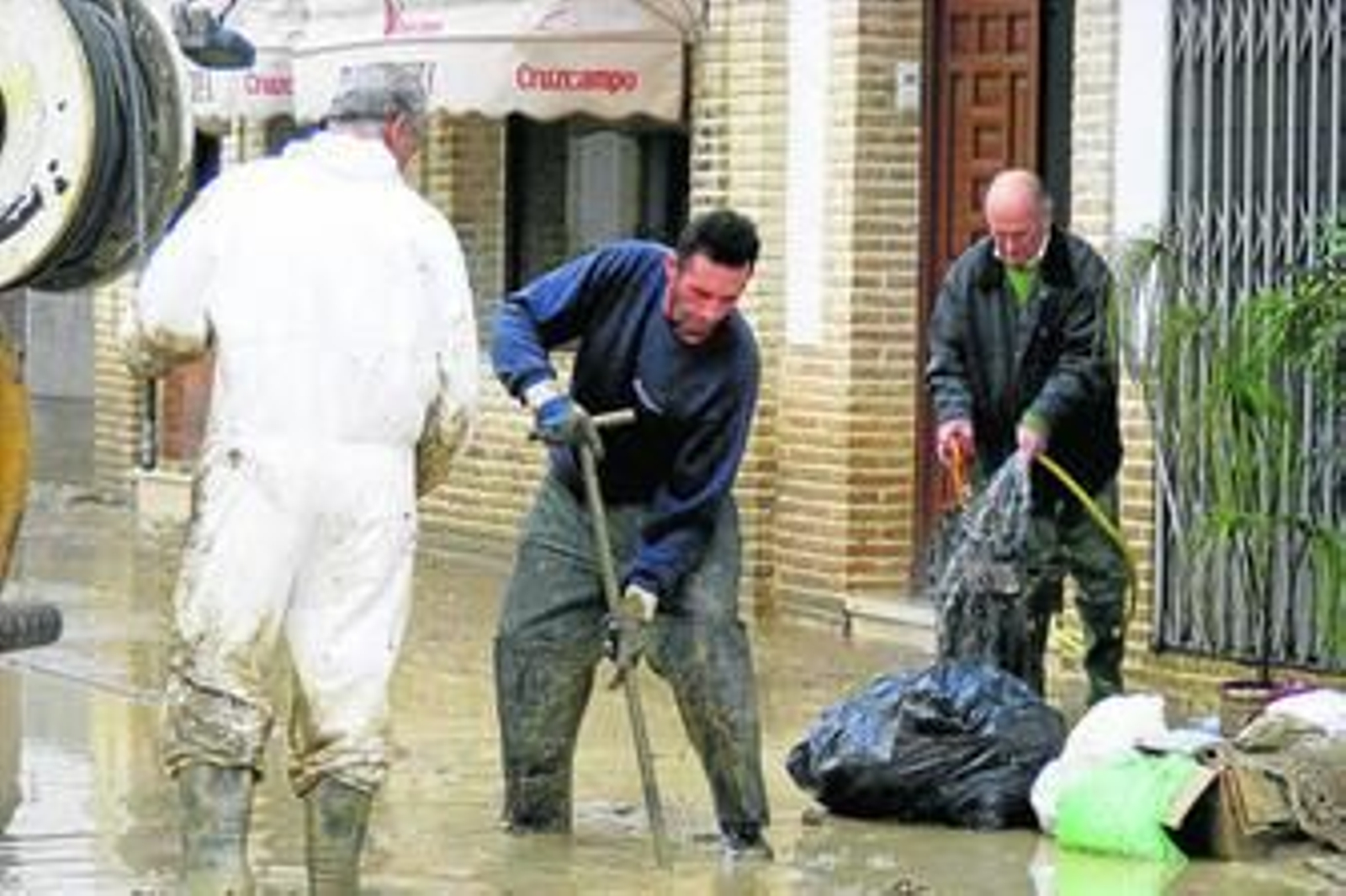 Operarios municipales retiran el lodo en una calle de Écija.