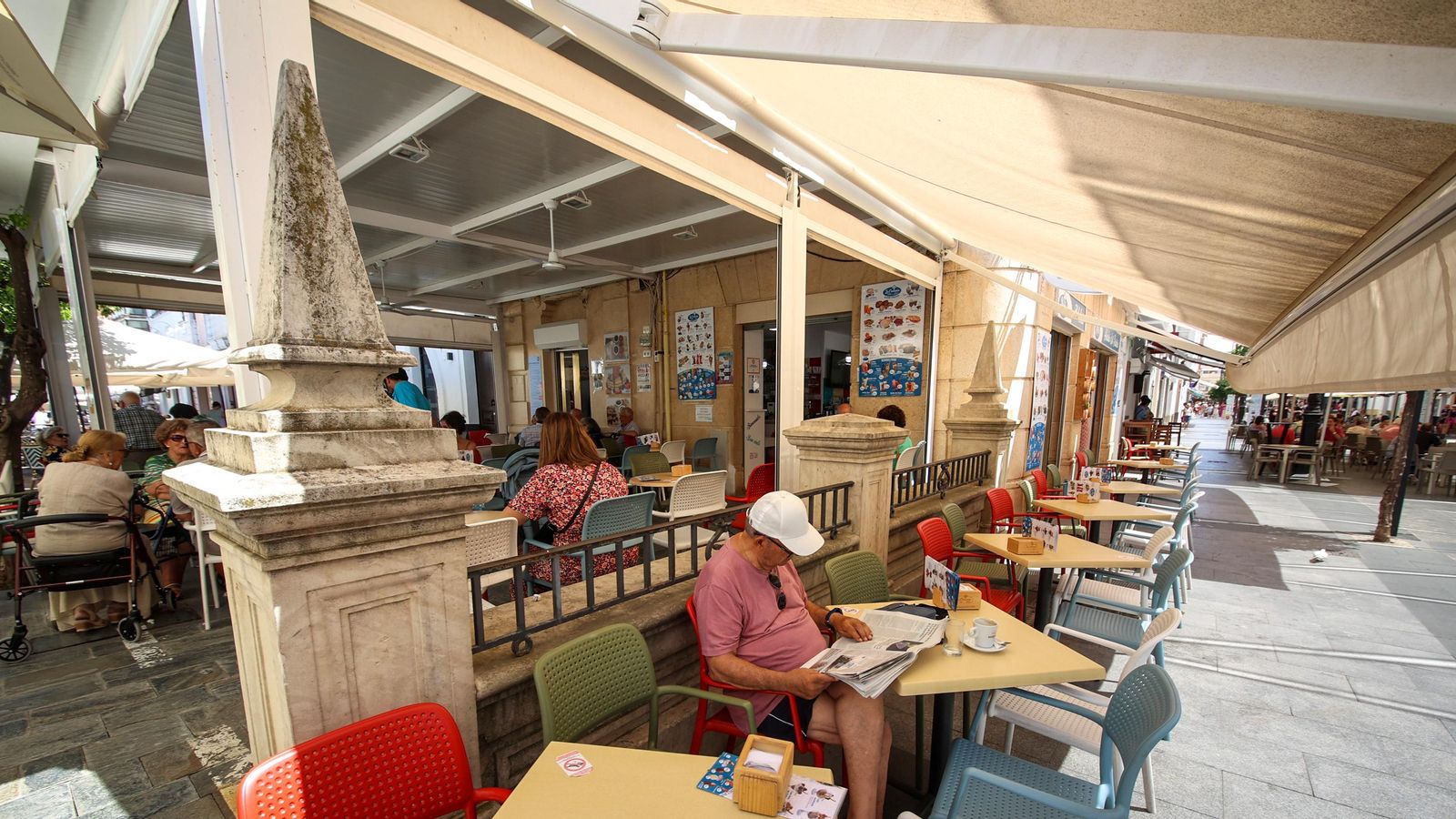 Un señor lee el periódico en la terraza de un establecimiento del centro de Sanlúcar.