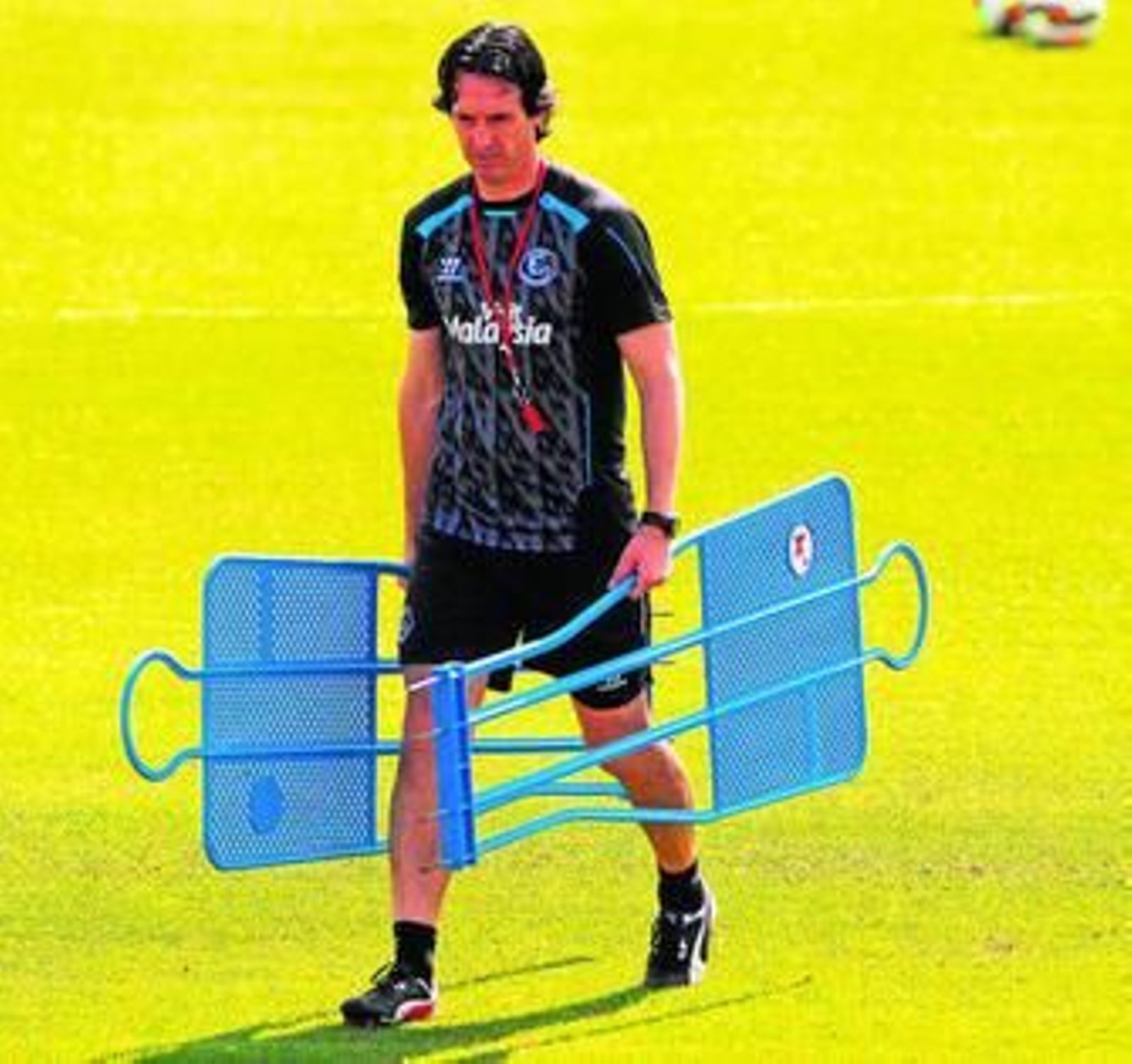 Unai Emery carga con dos elementos del material de entrenamiento en el día de ayer.