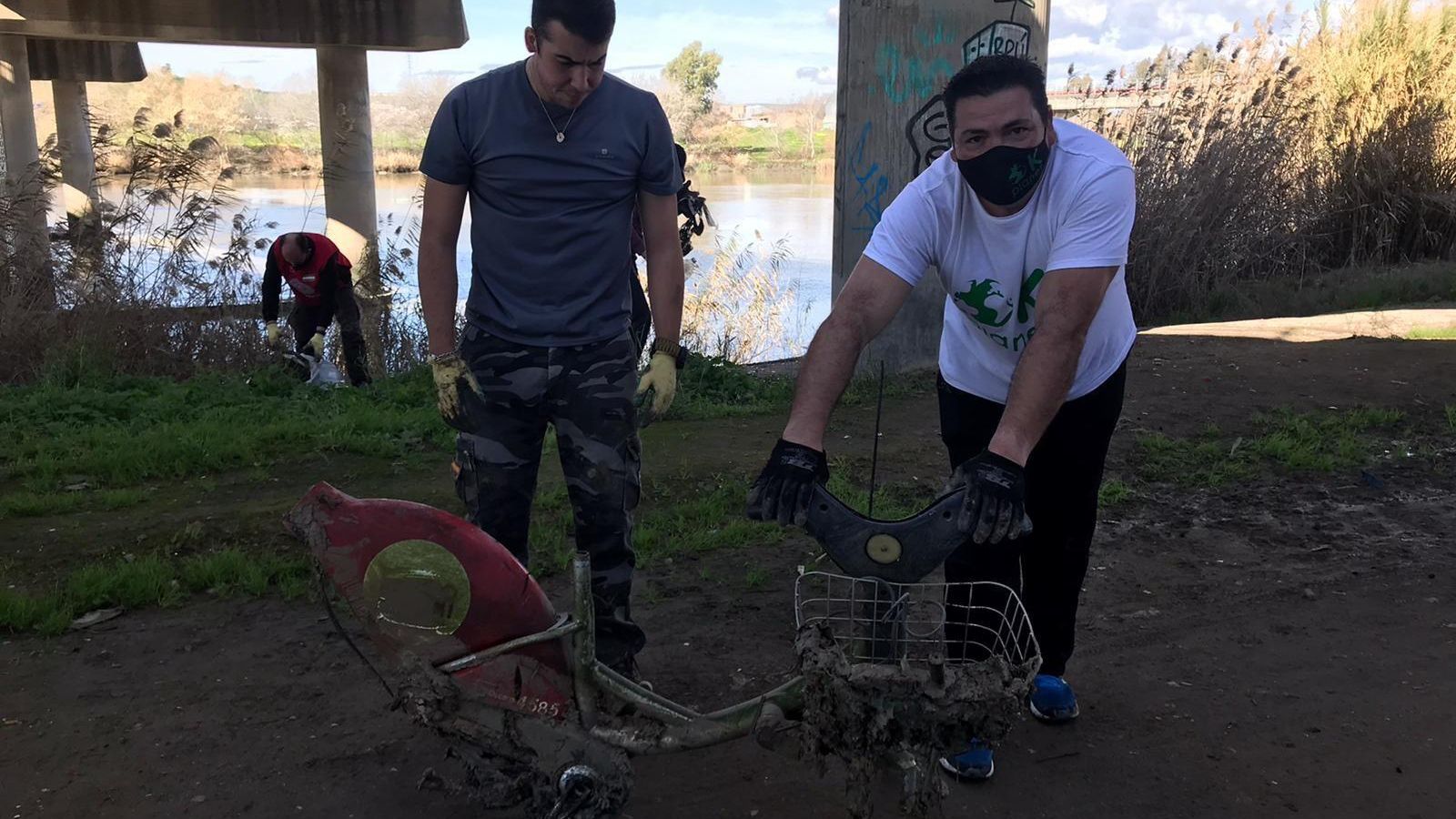 Dos voluntarios muestran lo que queda de una de las bicicletas de Sevici recuperadas.