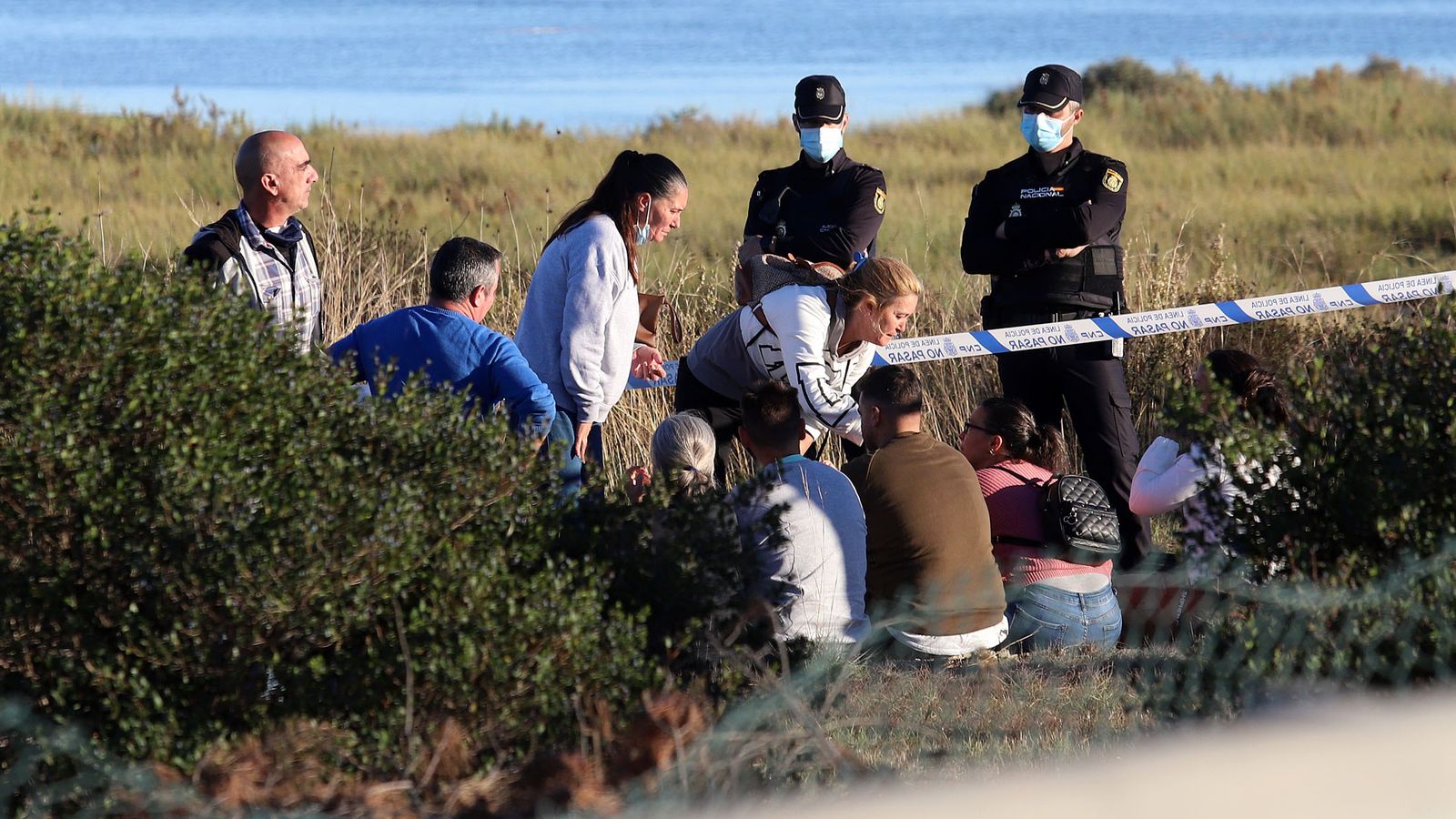 Familiares de los desaparecidos ante el cordón policial en el lugar donde se encontró el vehículo.