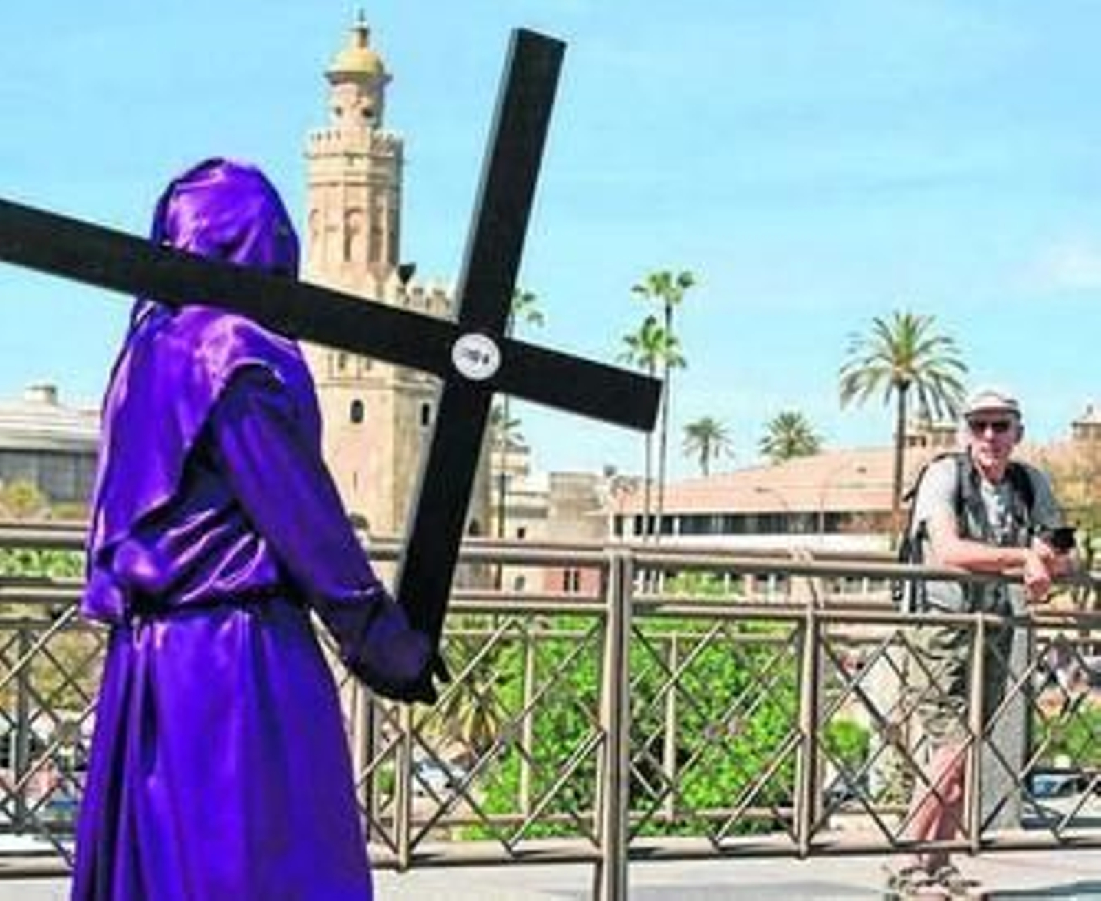 Un turista contempla el discurrir de la cofradía de las Cigarreras.