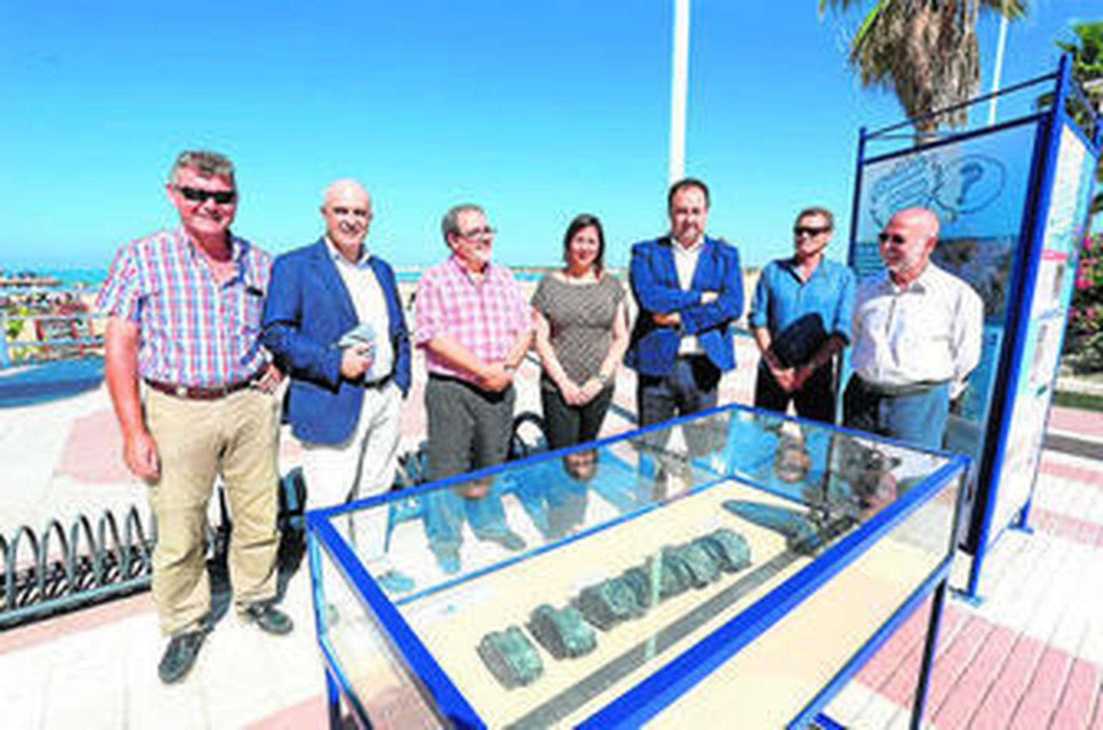 Los diferentes representantes de las entidades colaboradoras posan frente a una de las vitrinas con fósiles.