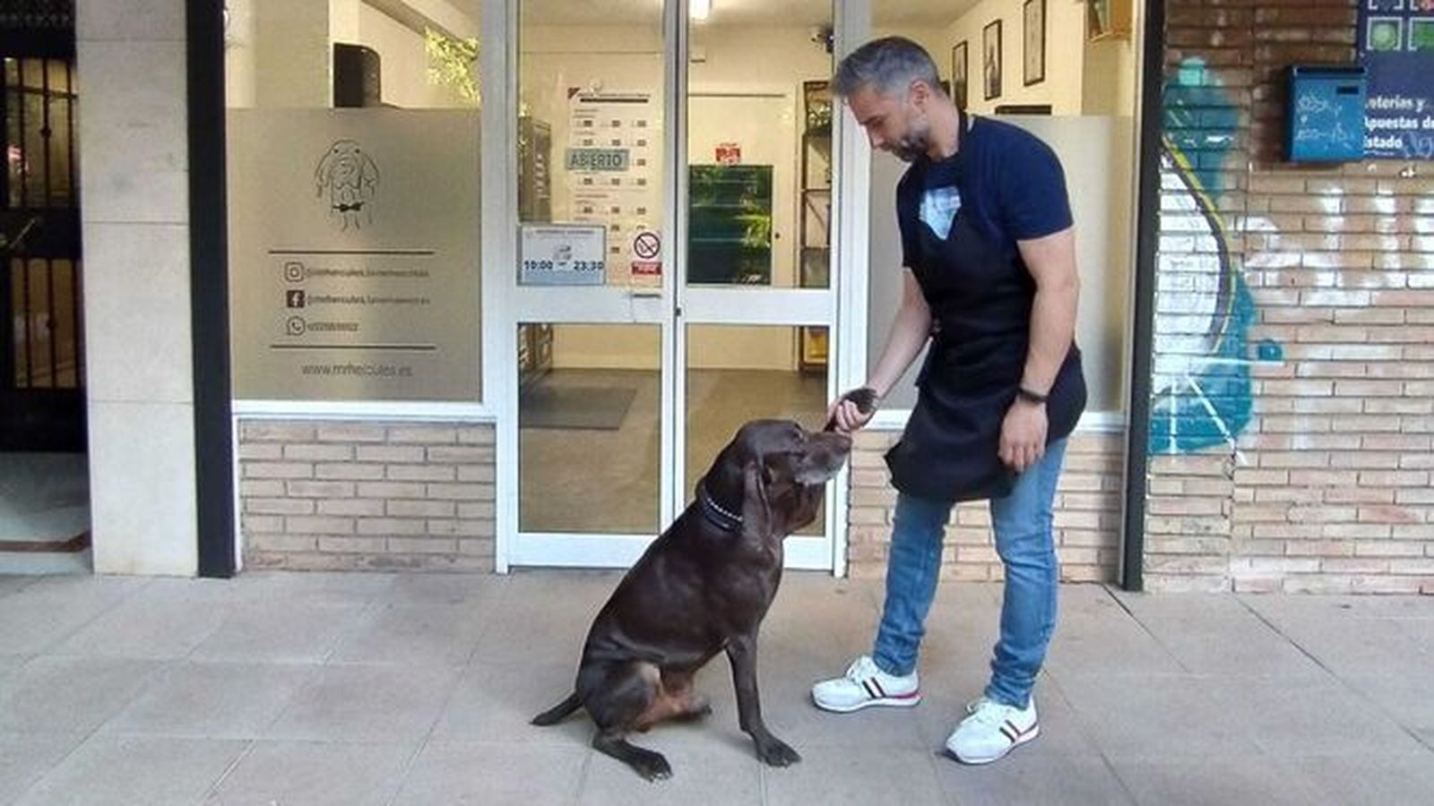 Jesús Martín en la puerta de su peluquería canina con su perro Hércules.