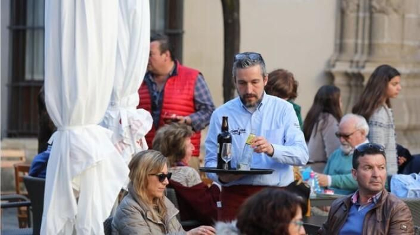 Un camarero atiende a los clientes en la terraza de un bar.