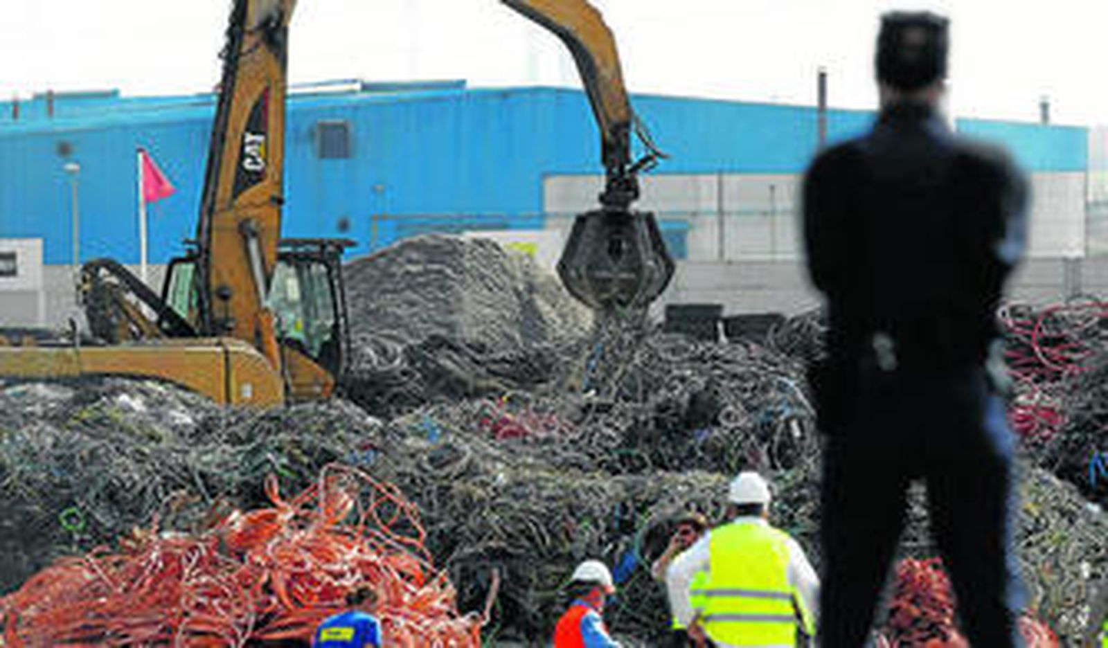 Un policía observa las labores de los técnicos entre toneladas de cobre.