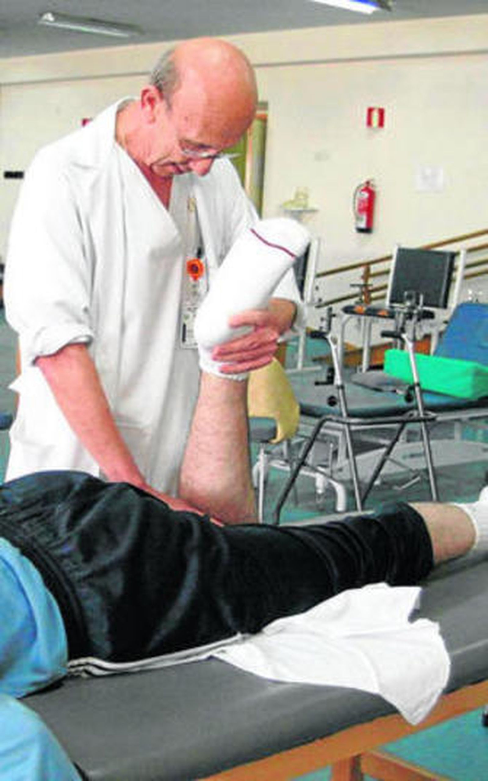 Un fisioterapeuta realiza ejercicios a un paciente.