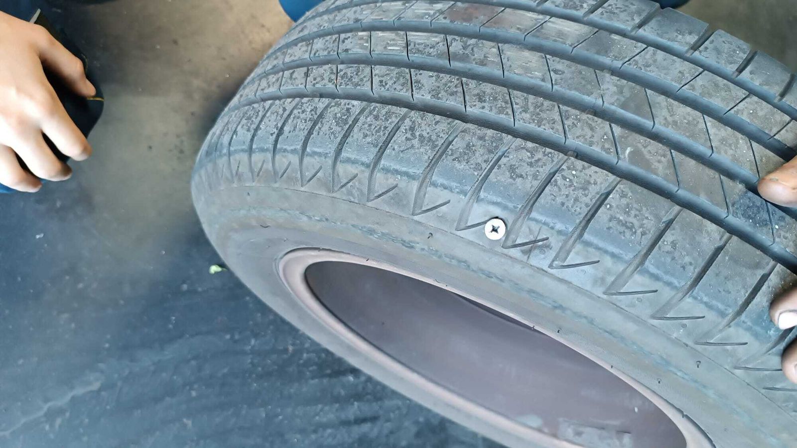 La rueda pinchada del coche de un profesor con uno de los clavos más habituales en el suelo del aparcamiento, tornillos.