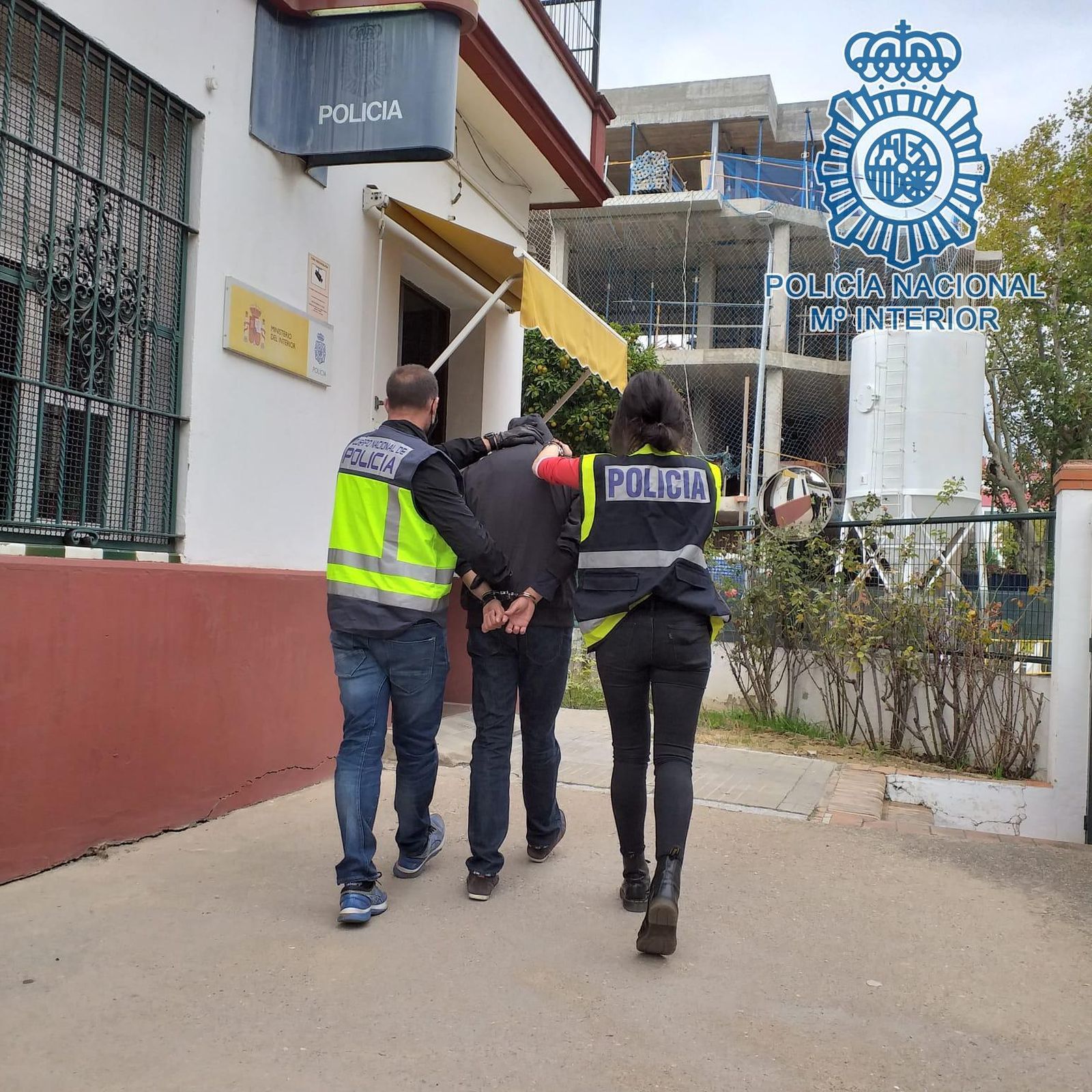 Dos policías nacionales trasladan al detenido a la comisaría del distrito Nervión.