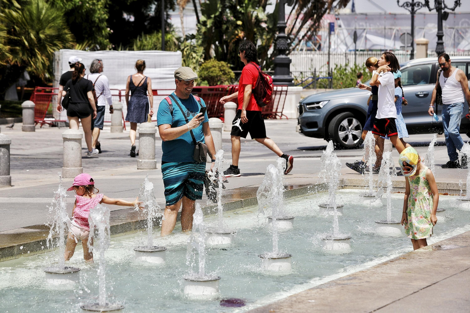 Una familia procura aliviarse del calor disfrutando de paso de los chorros de una de las fuentes de San Juan de Dios.