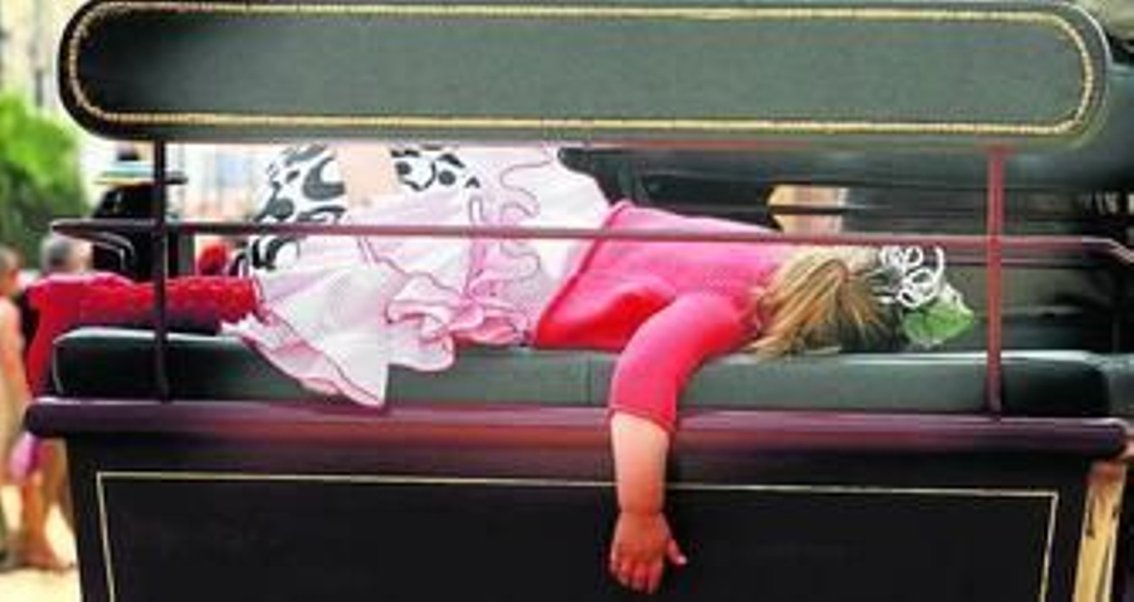 Una niña vestida de gitana, derrotada ya a estas alturas de la Feria, dormida en un enganche.