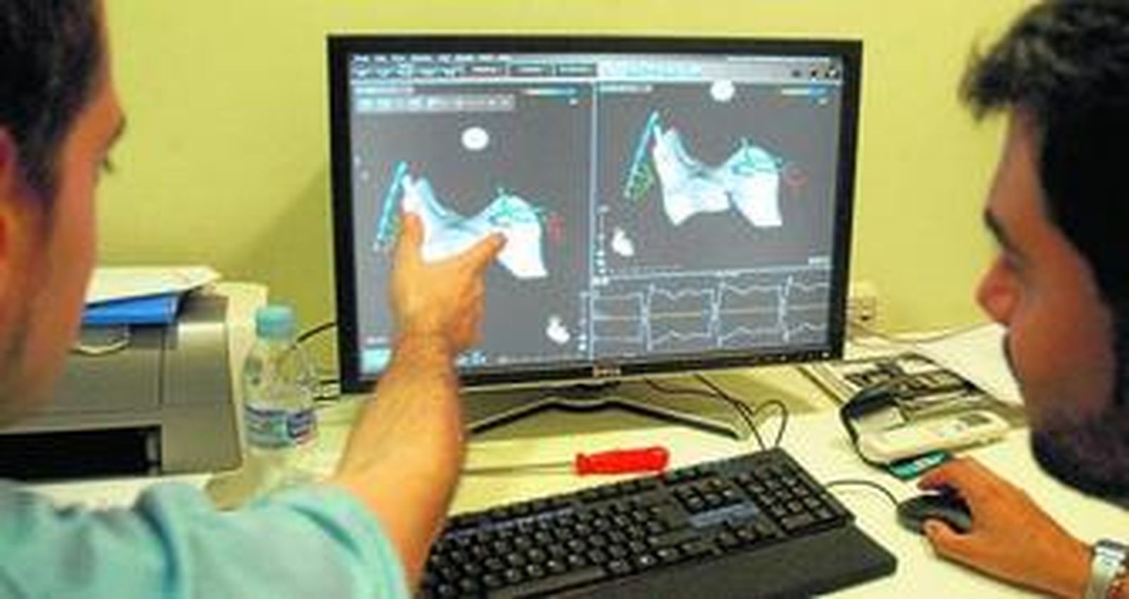 Dos especialistas observan en la pantalla de ordenador la colocación de un catéter.