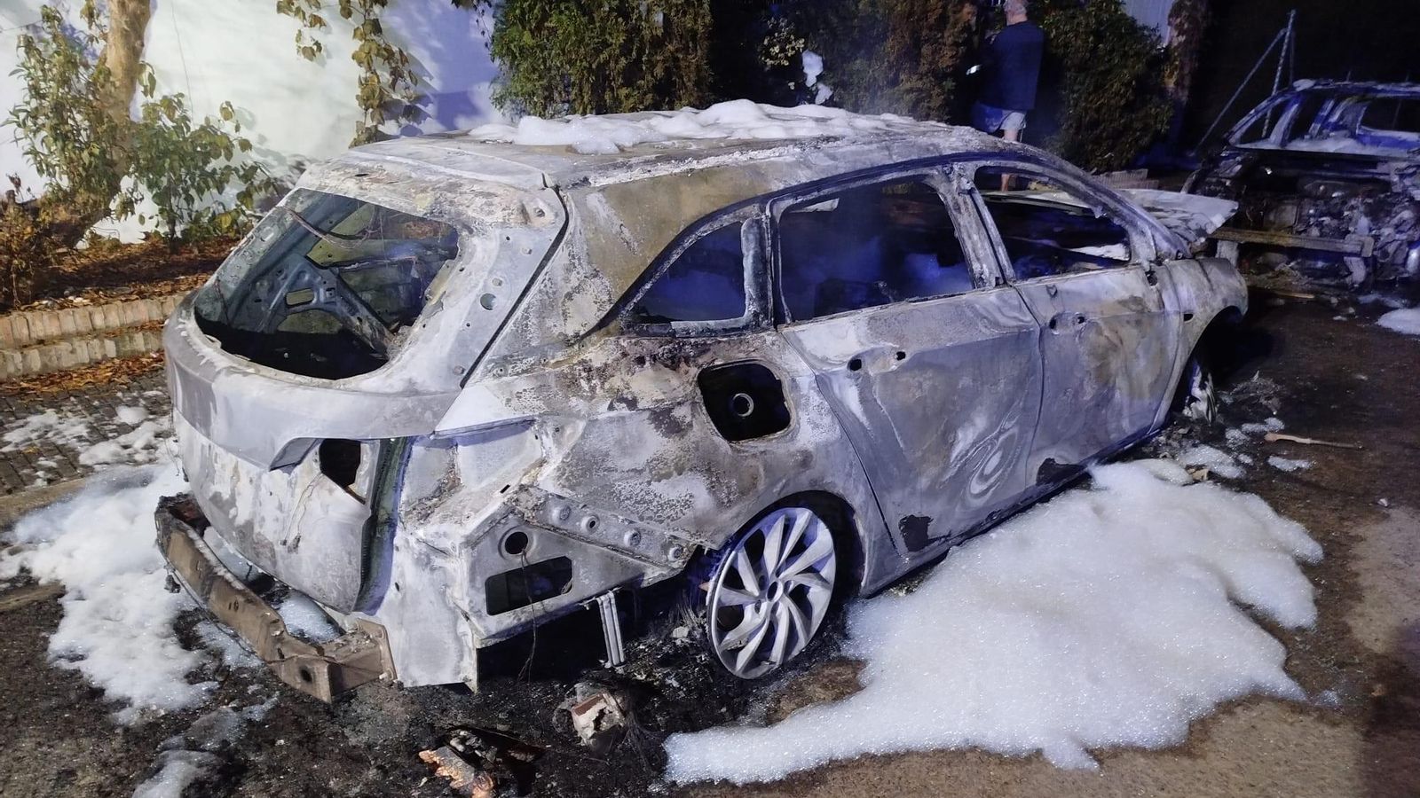 Un vehículo quemado tras la intervención de los bomberos para apagar las llamas.