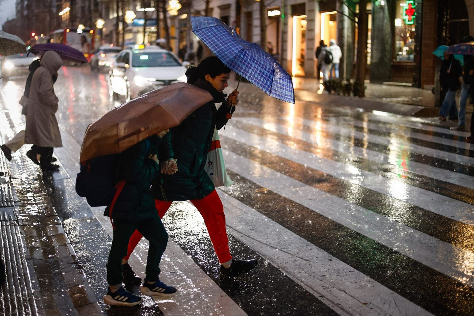 Varias personas caminan bajo la lluvia este martes.