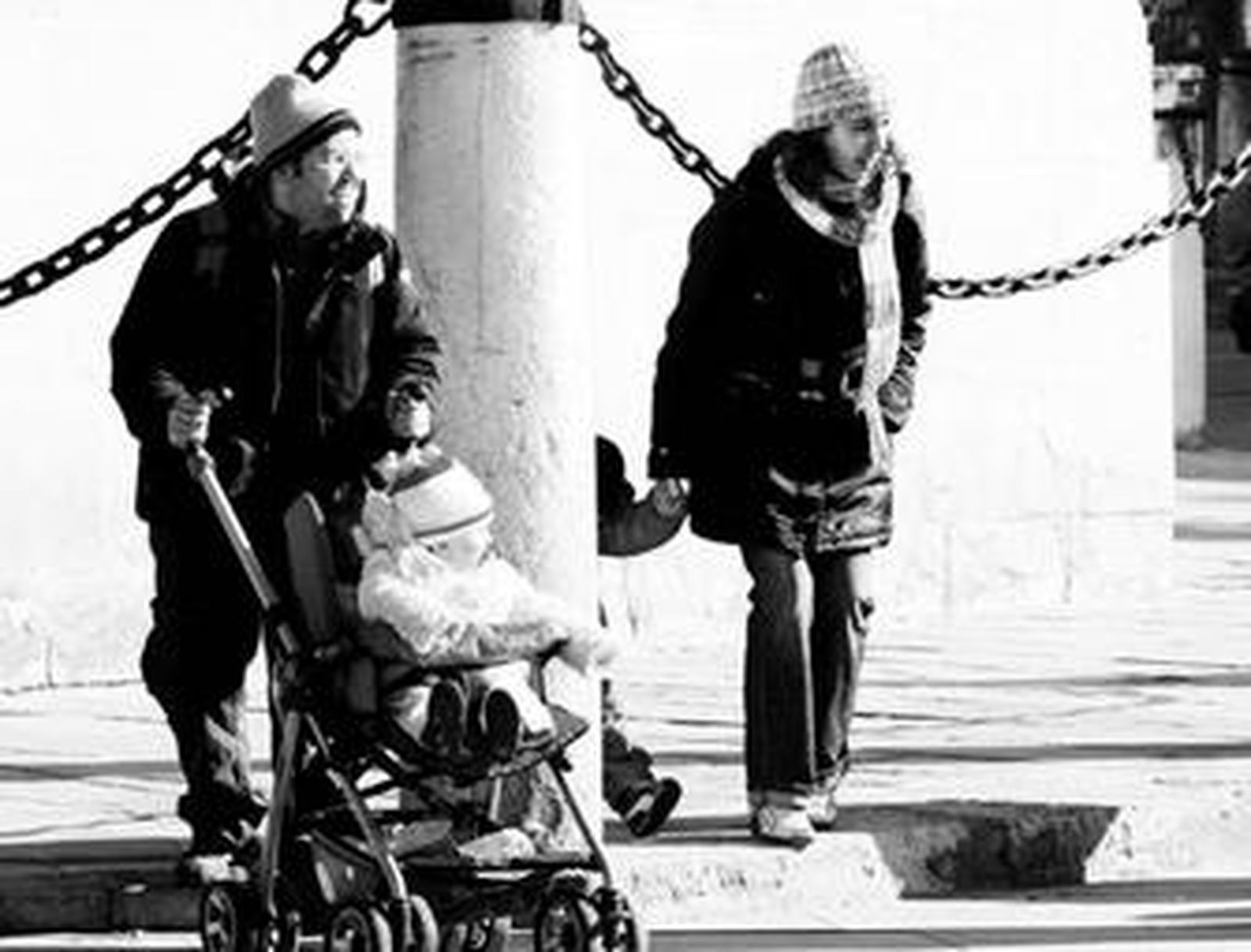 Unos turistas protegen a sus hijos del frío en las gradas de la Catedral.