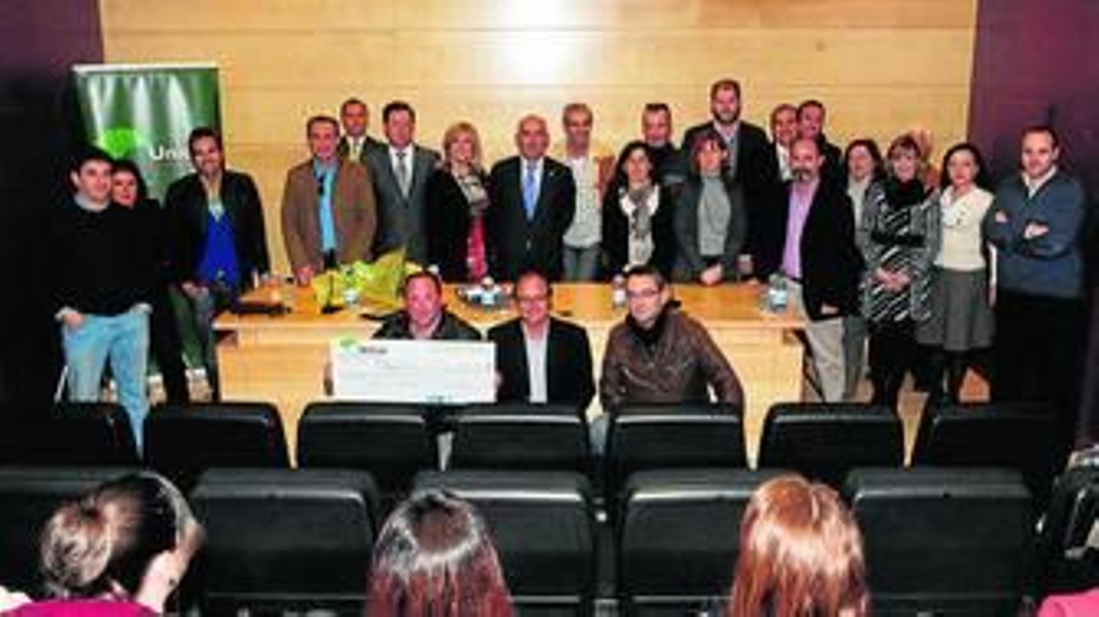 El representante de la comunidad premiada posa con un cheque simbólico, junto a los administradores.