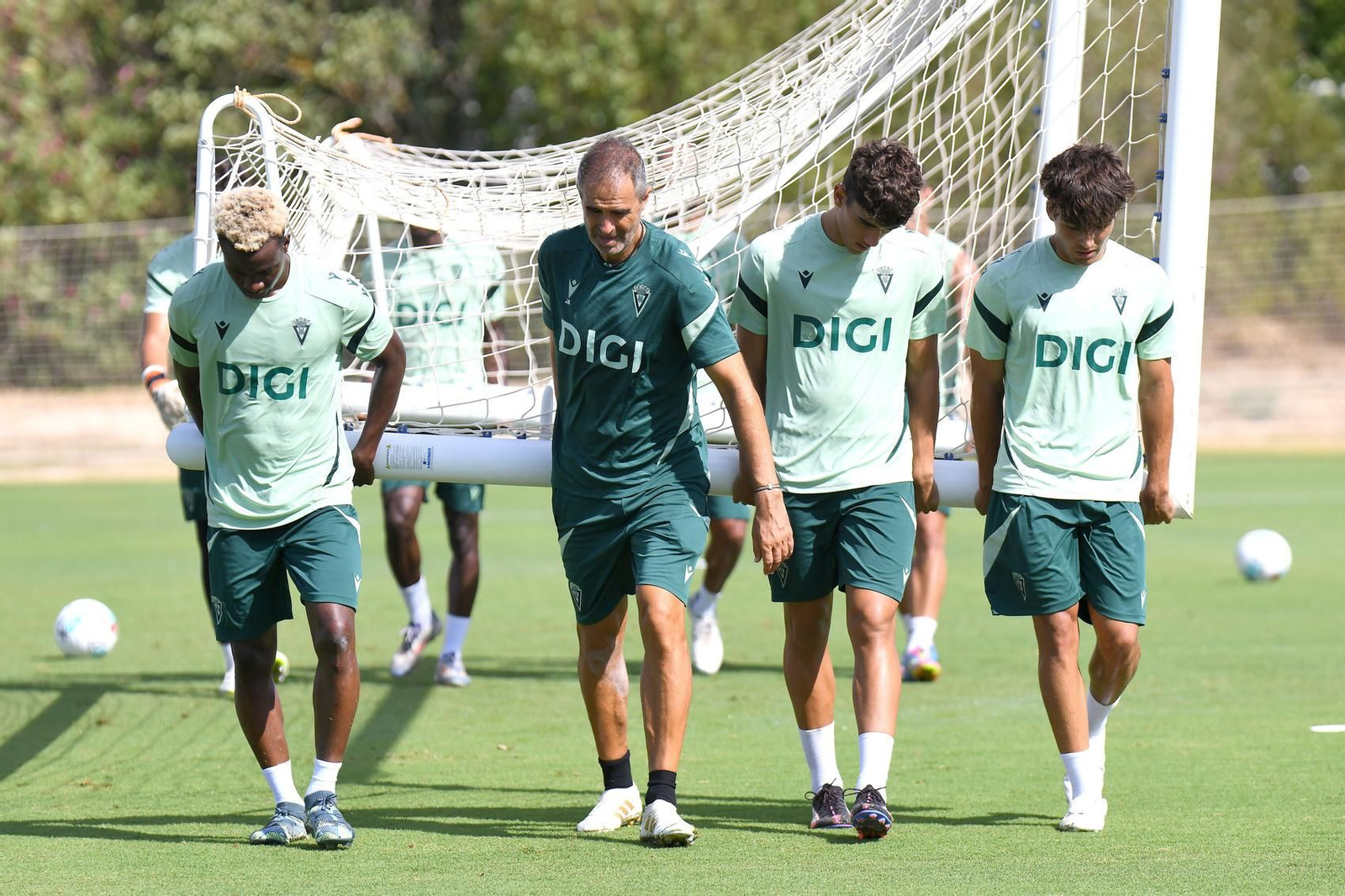 Gaizka Garitano ayuda a cargar una portería portátil en un entrenamiento.