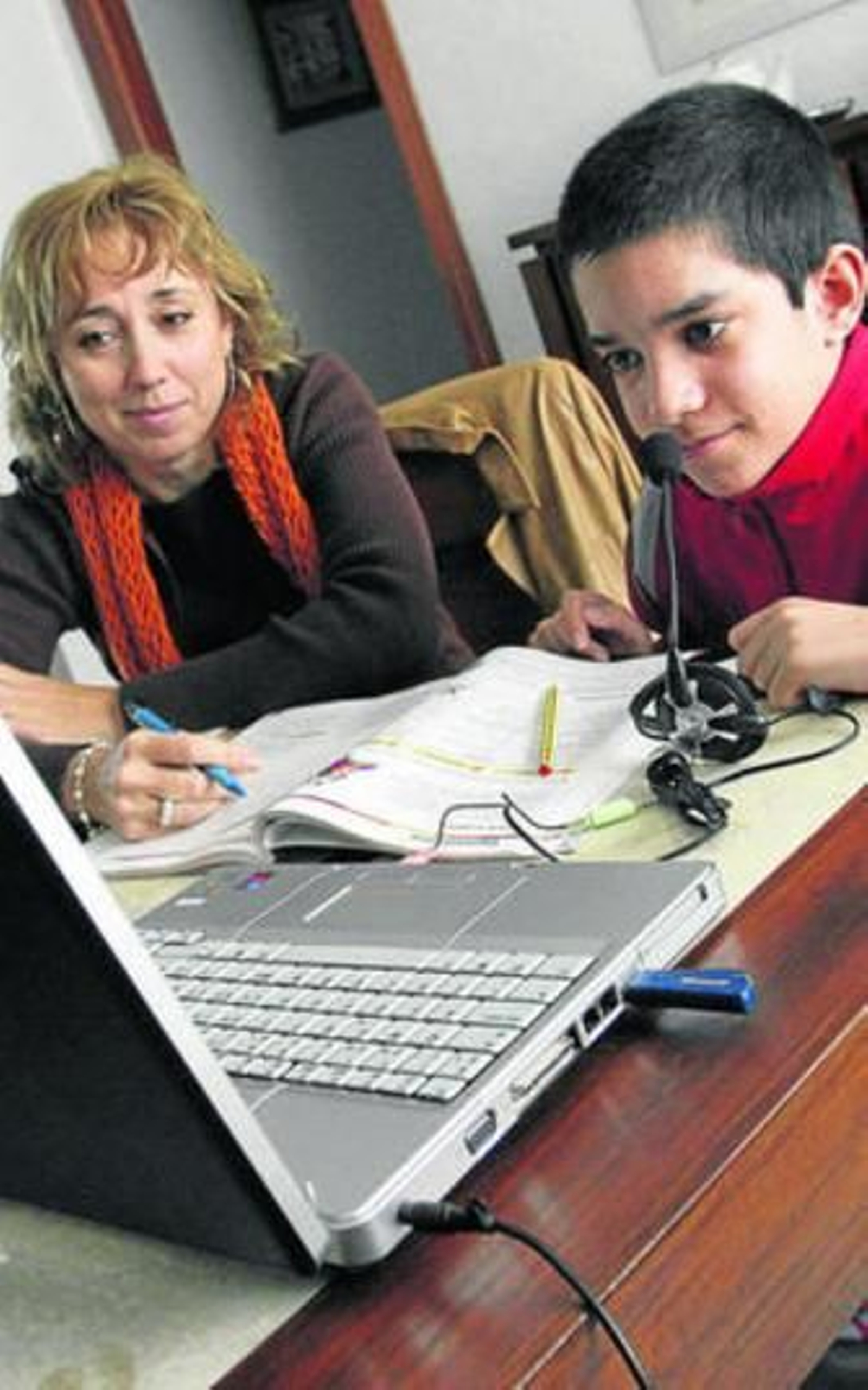 Una profesora da clases particulares a un niño en su casa.