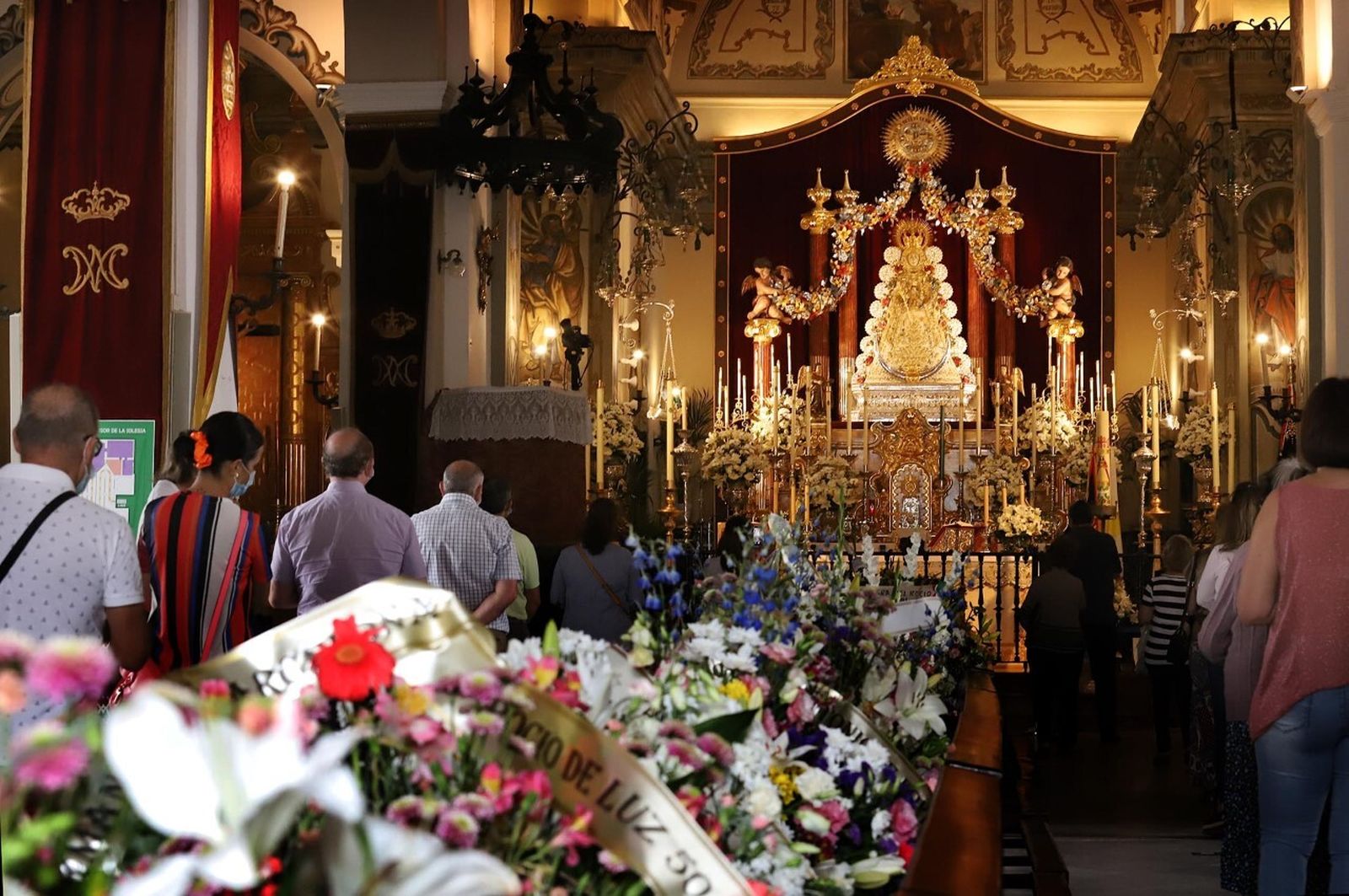 El pasillo central se encuentra inundado de ramos de flores de ofrenda a la Blanca paloma