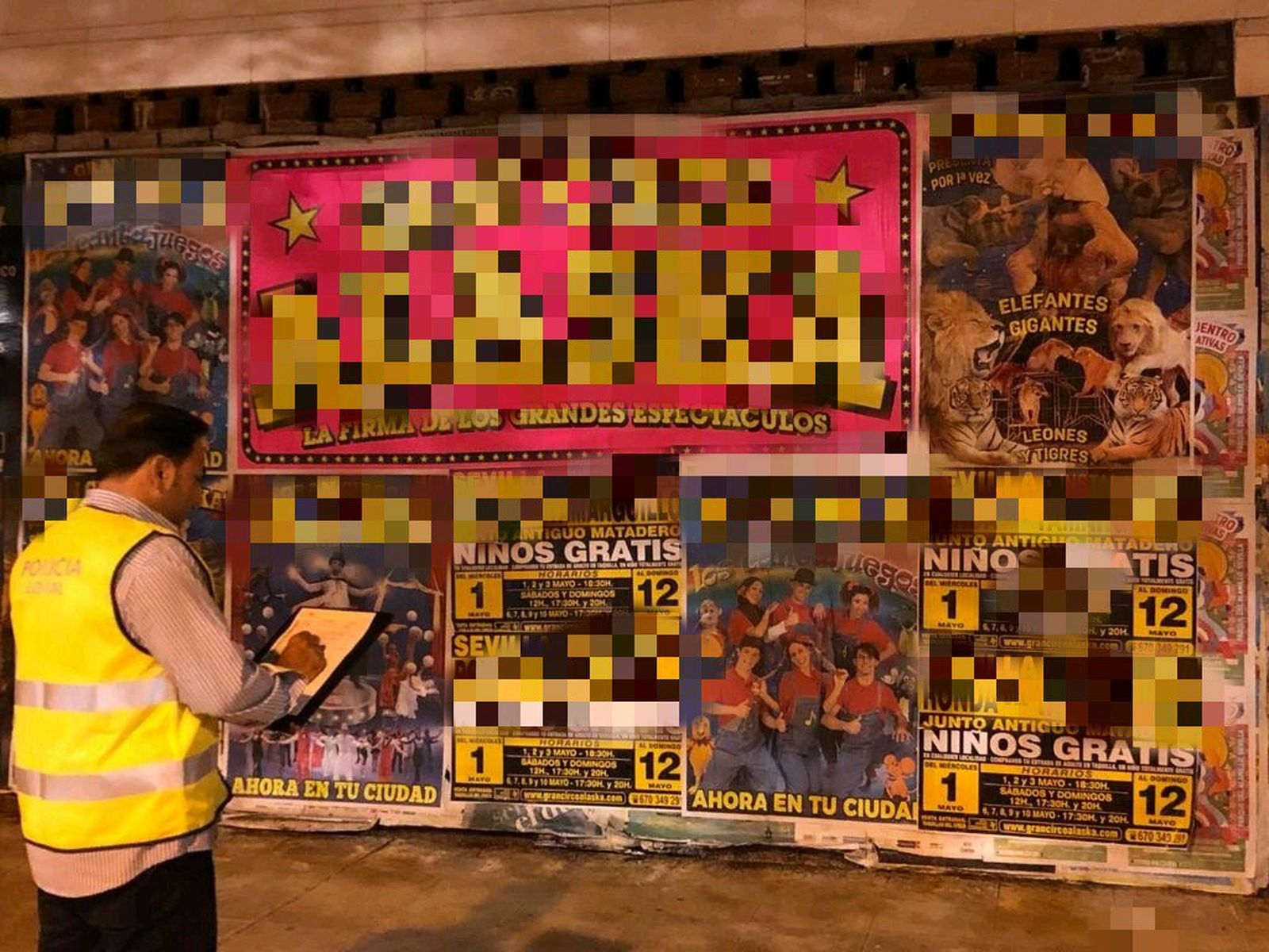 Un agente de la Policía Local ante varios carteles pegados en Sevilla.