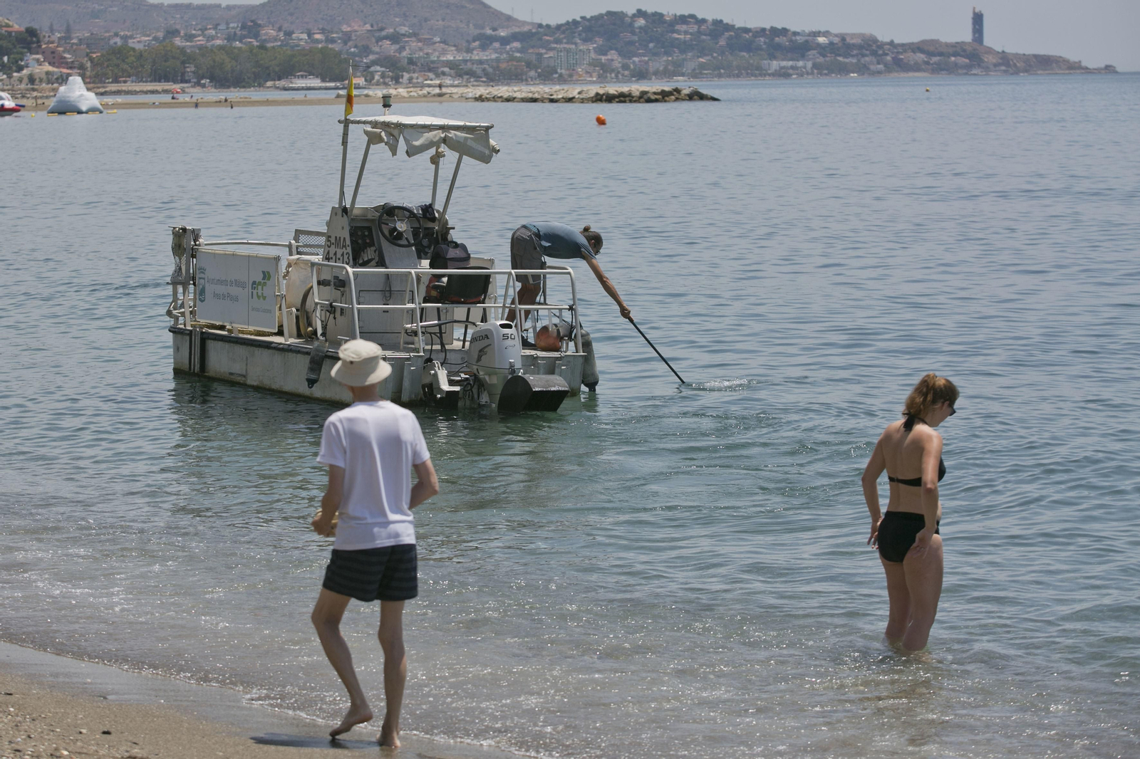 Un barco recoge medusas este lunes en La Malagueta.